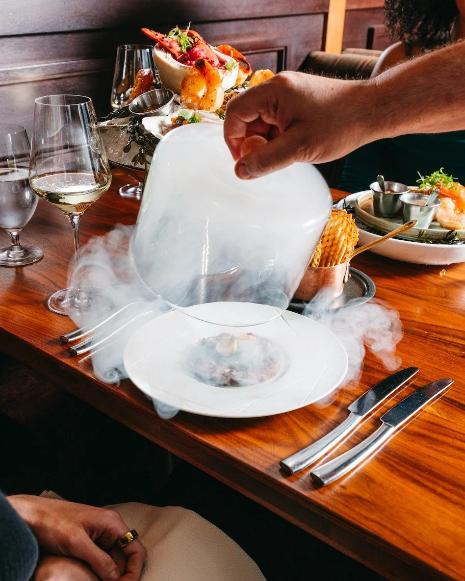Lift, reveal, and savor every bite of our Beef Tartare.

Texas Wagyu, puffed tendon, caper powder, and garlic-dijon aioli come together in a dish designed as much for the experience as the flavor.