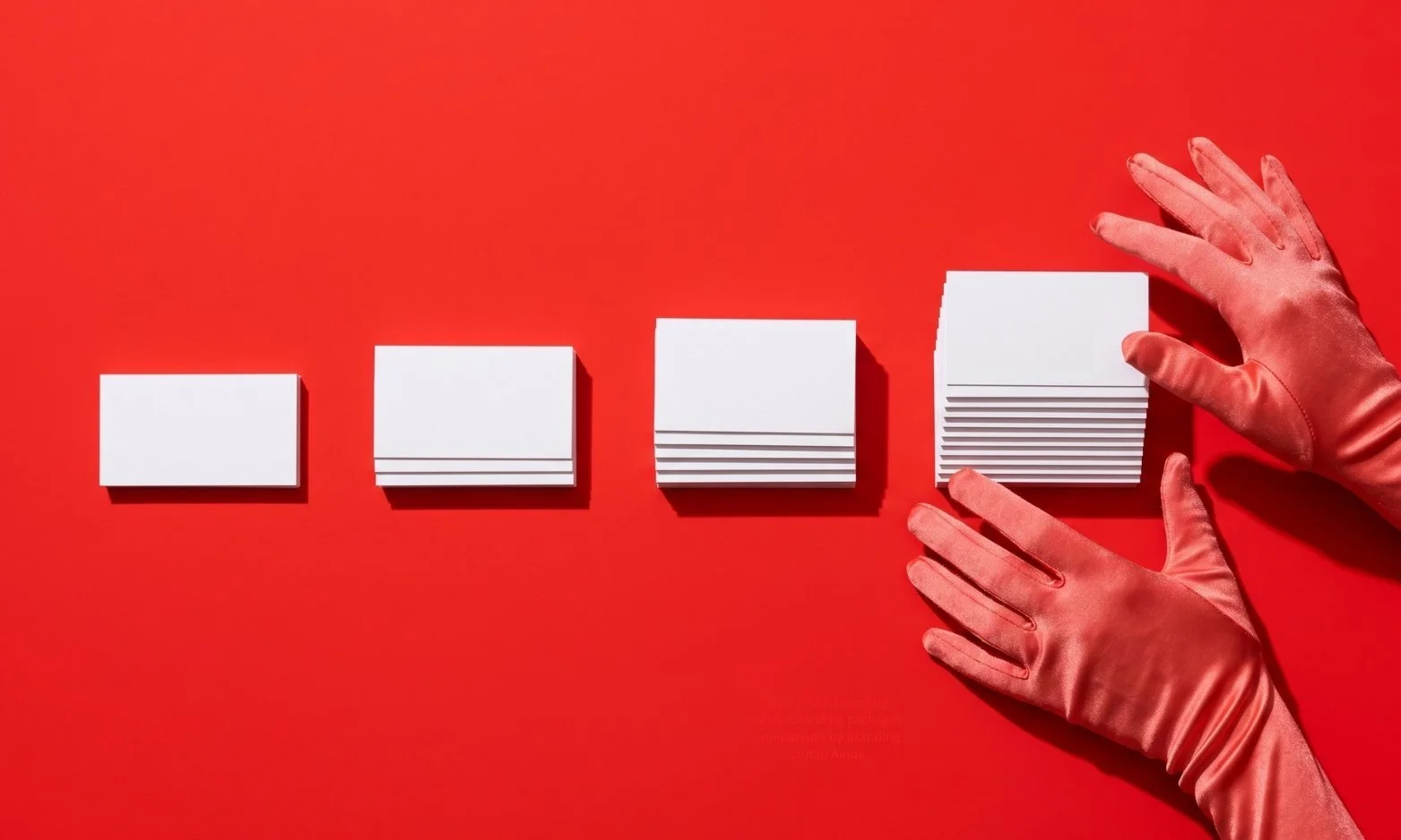 Hands organizing pile of card stacks, the piles grow in size from left to right. The image symbolizes a scaling brand and the ROI on branding.