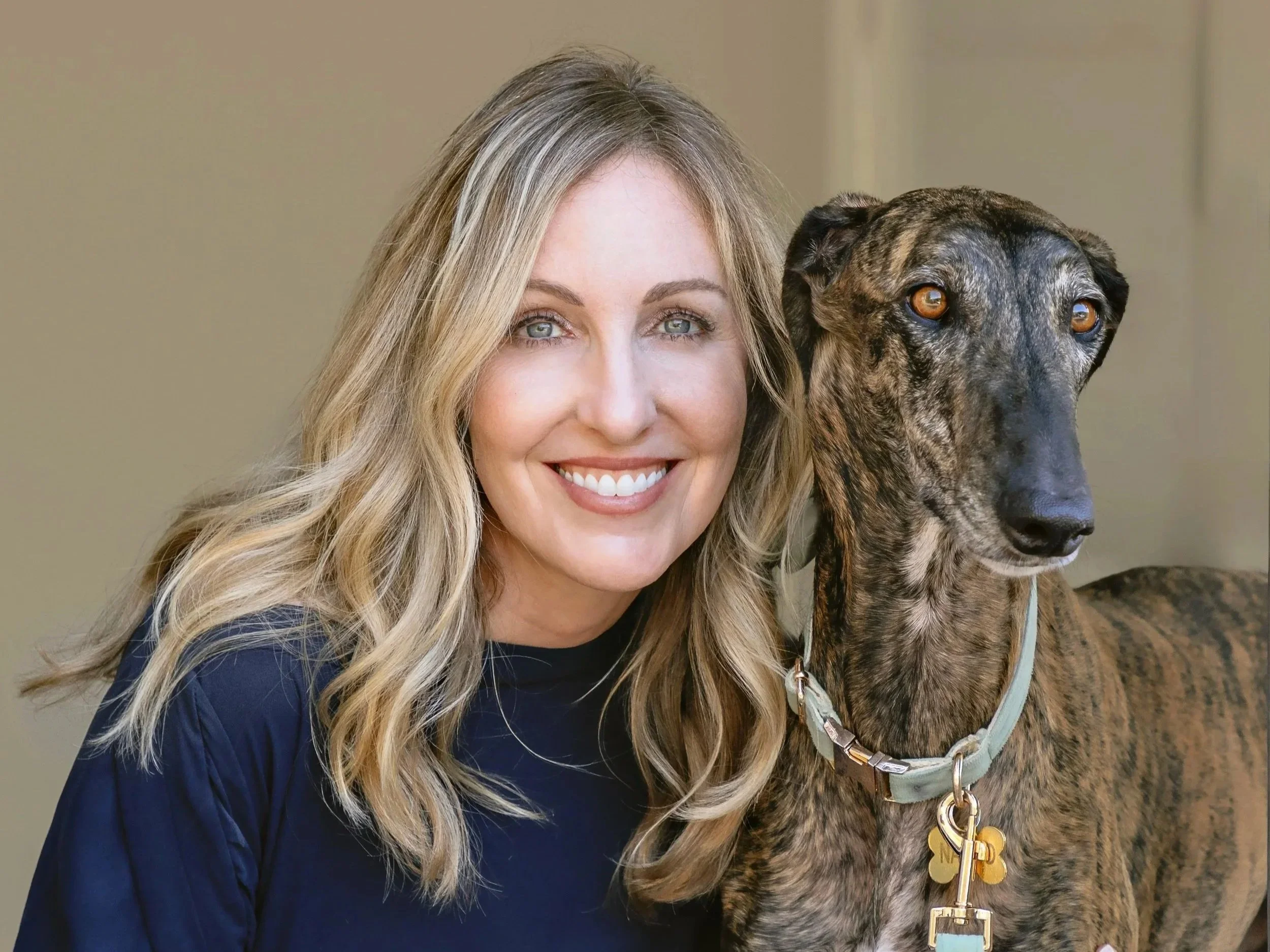 Picture of a woman with blonde hair and a brindle Spanish Greyhound