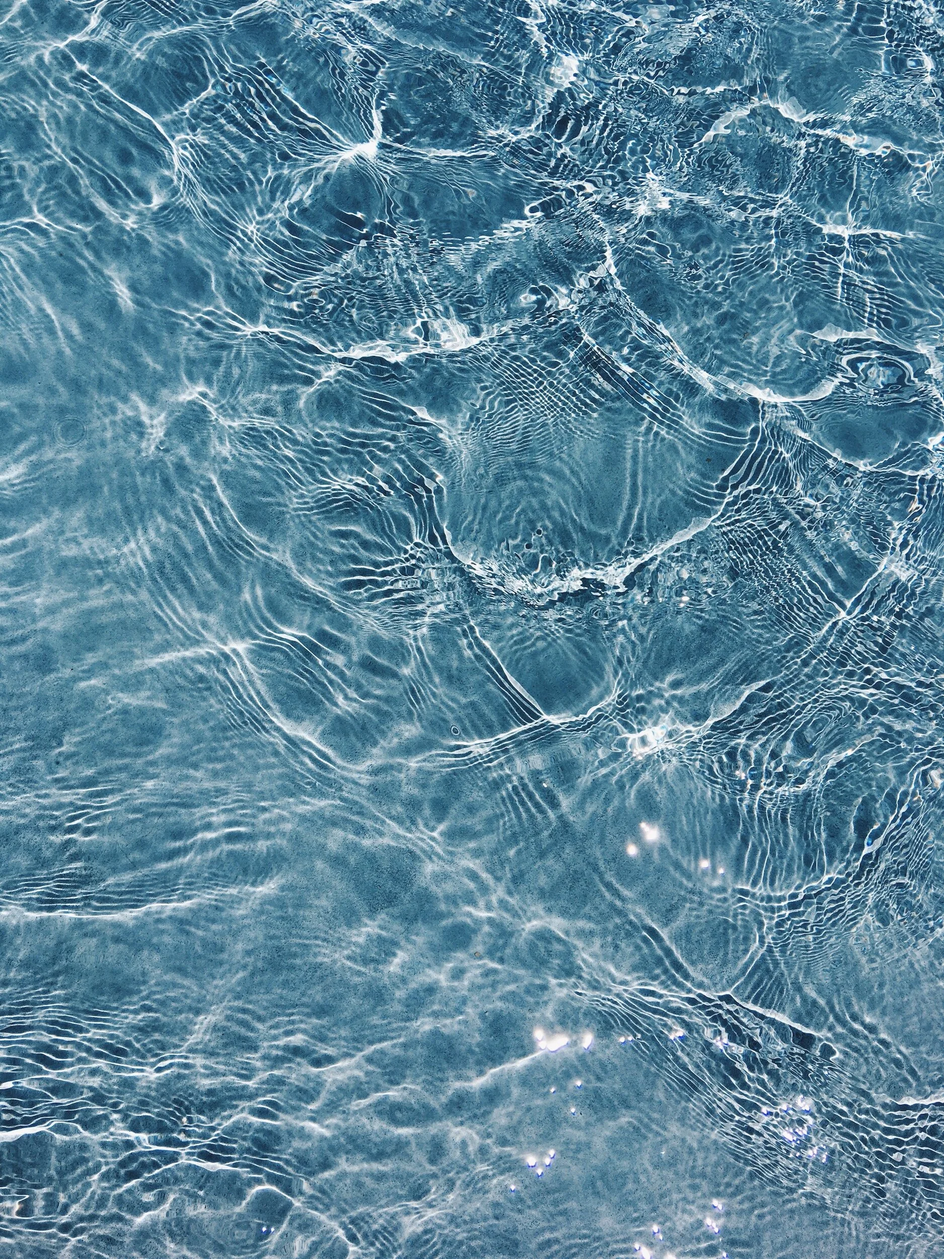 Close-up of clear blue water with ripple patterns and sunlight reflections.