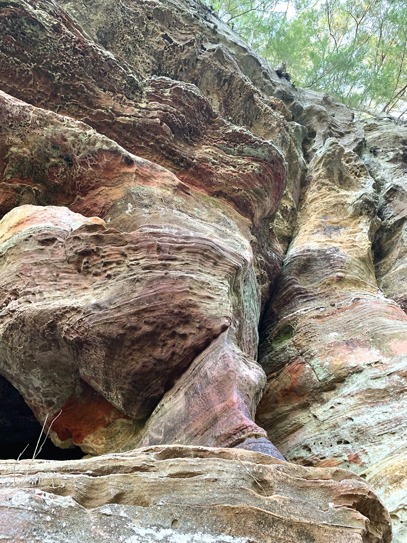 A cliff on the trail to the cave. The darker area between the two cliff sections may be an example of a geological joint.