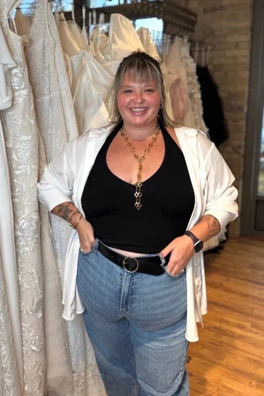 plus size woman standing in front of a rack of plus size wedding dresses