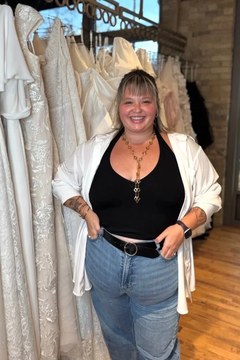 plus size woman standing in front of a rack of plus size wedding dresses