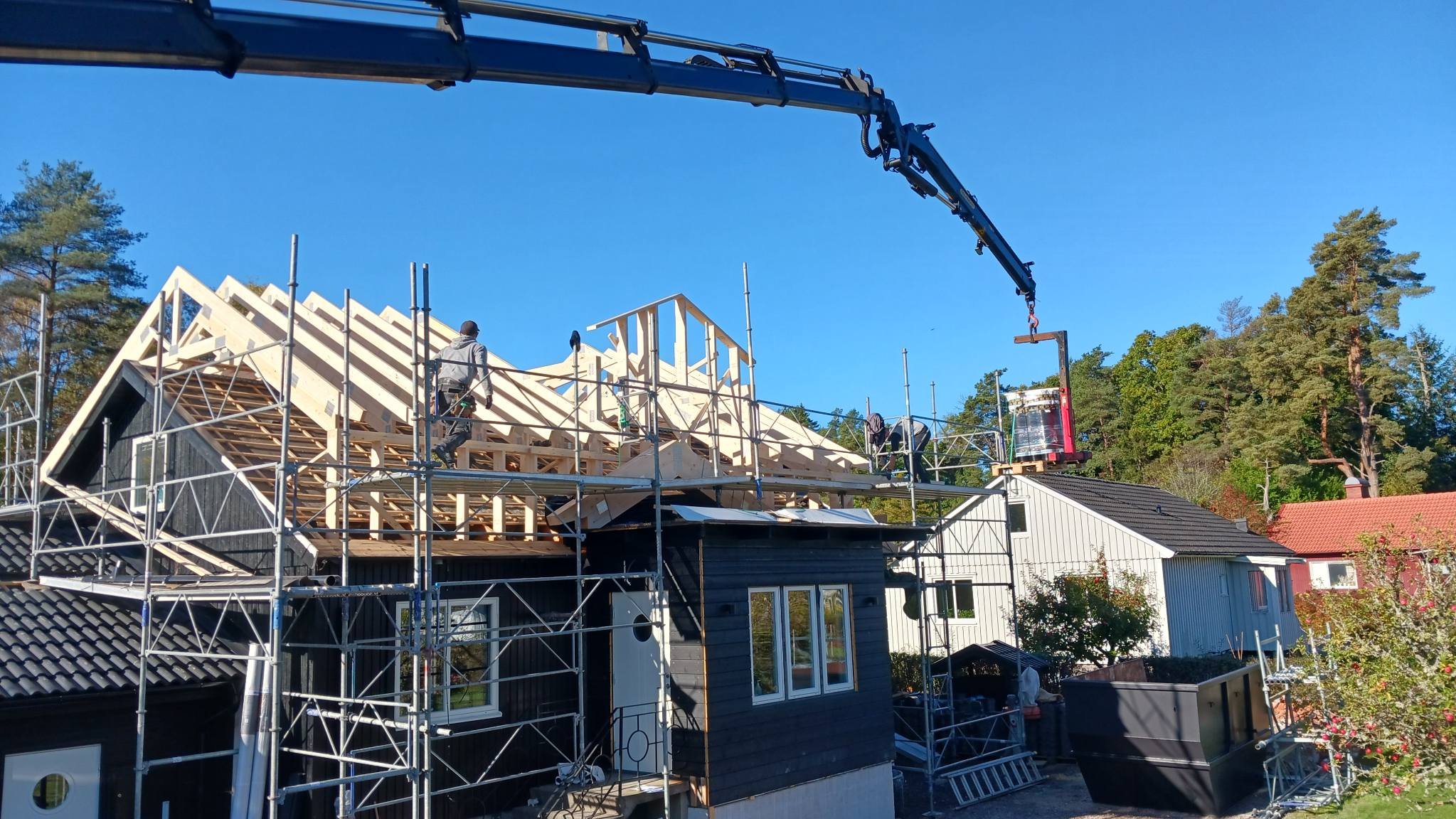 Kran och ett hus utan tak under konstruktion