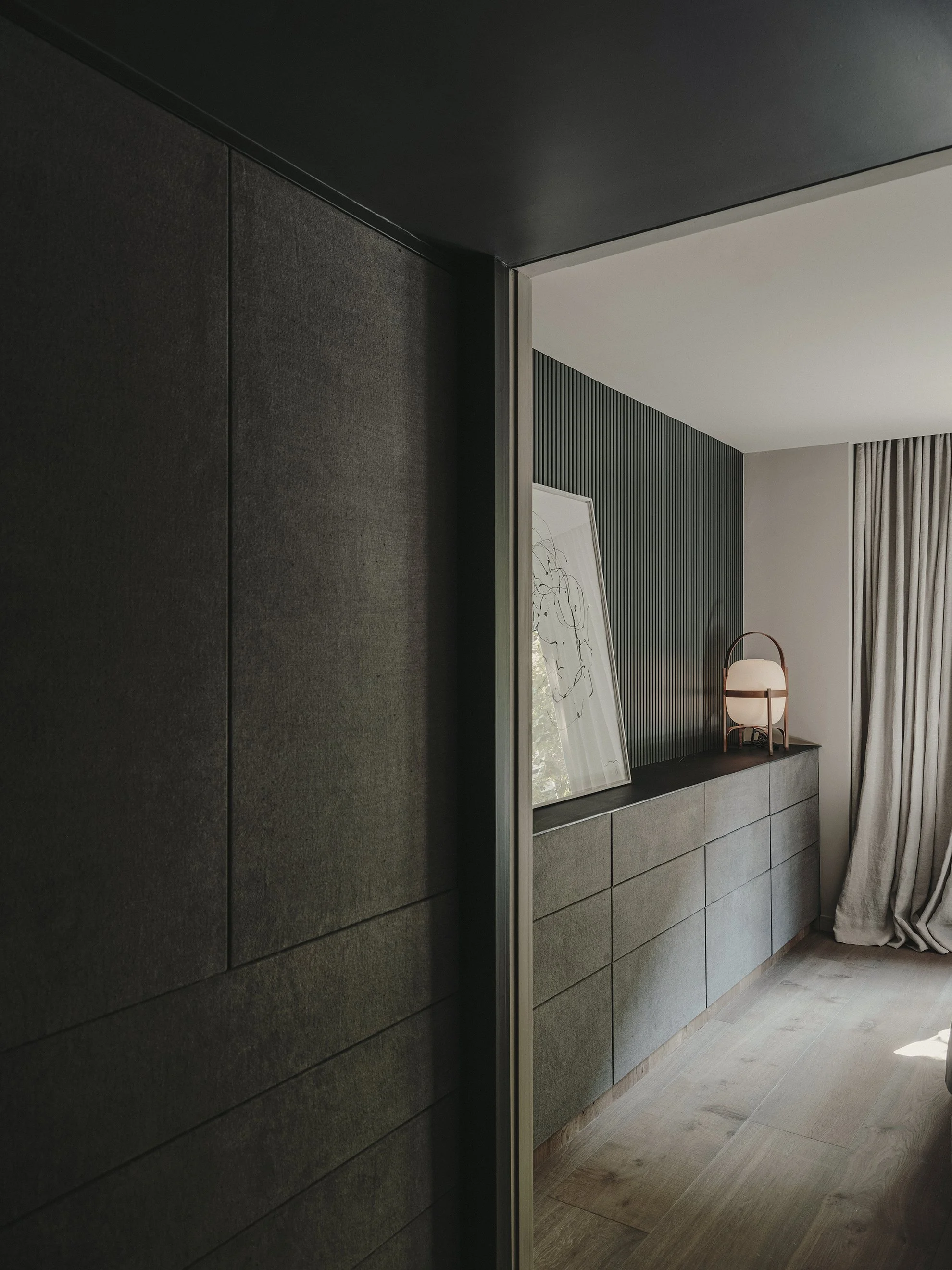 Dormitorio con cómoda, lámpara de mesa y espejo junto a las cortinas