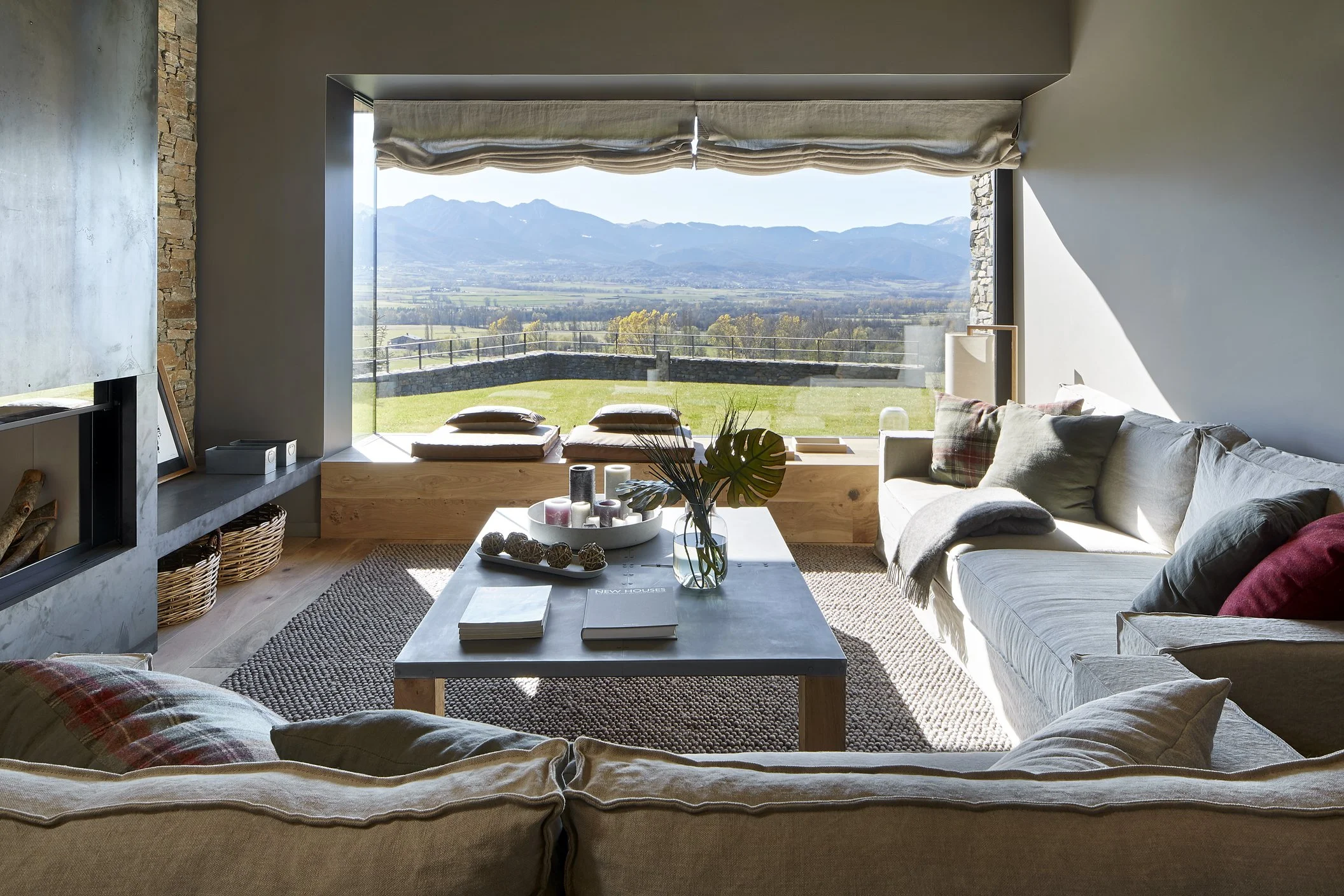 Salón con sofás grises y gran ventanal panorámico con vistas al valle
