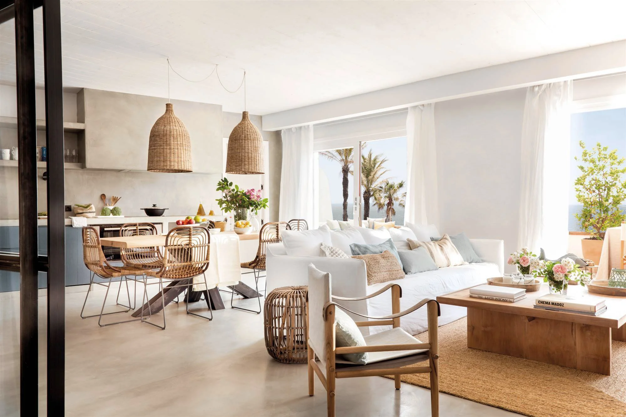 Salón de una vivienda reformada en Begur con sofá blanco, mesa de madera y lámparas colgantes de fibra