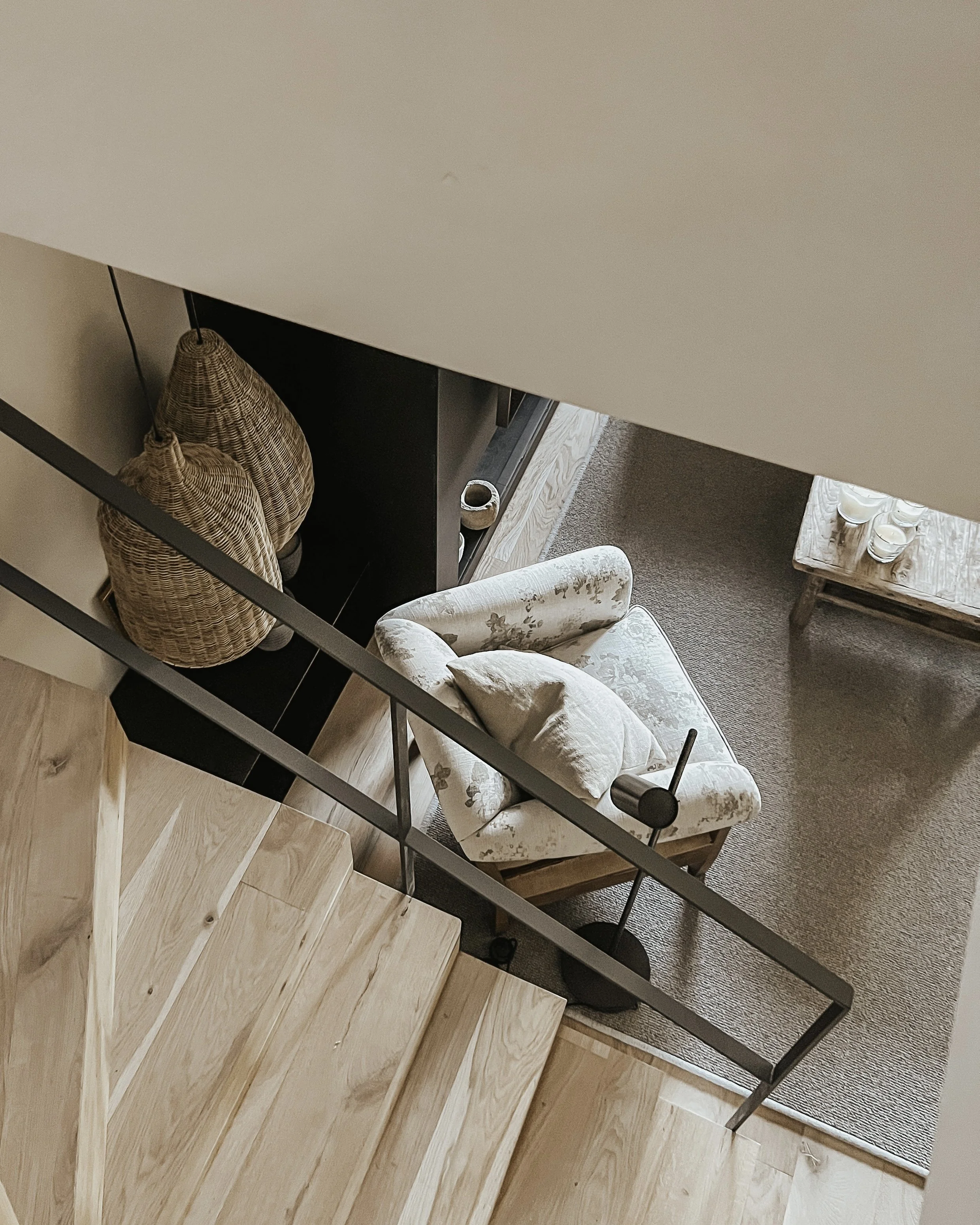 Salón visto desde la escalera, con sofá, cojines y suelo de madera