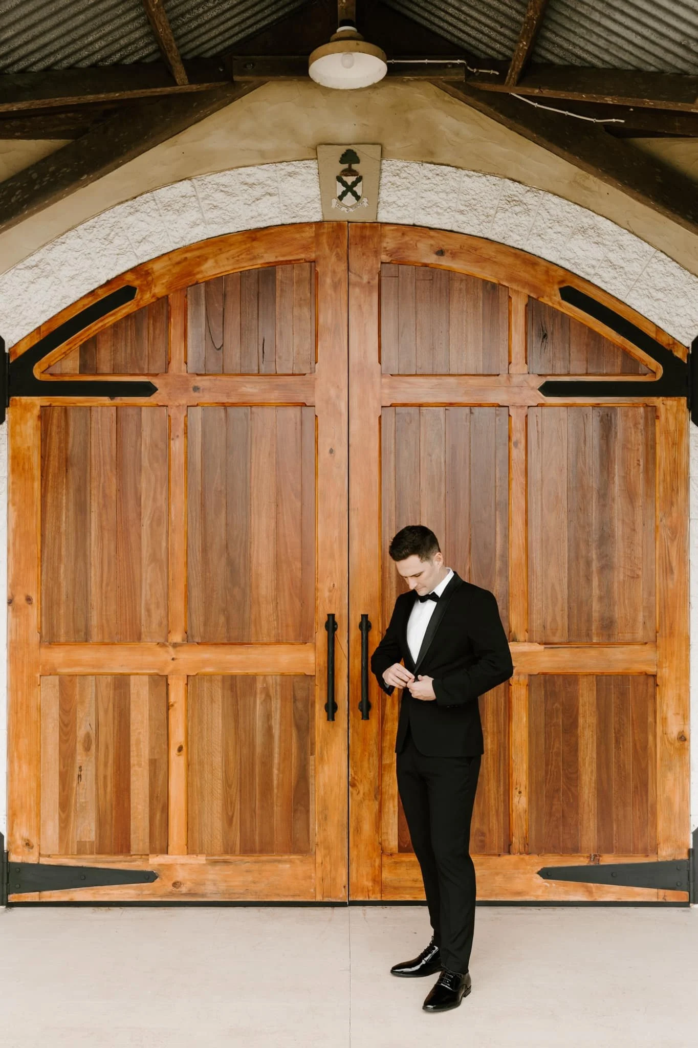 Groom standing against Flaxton Gardens archway