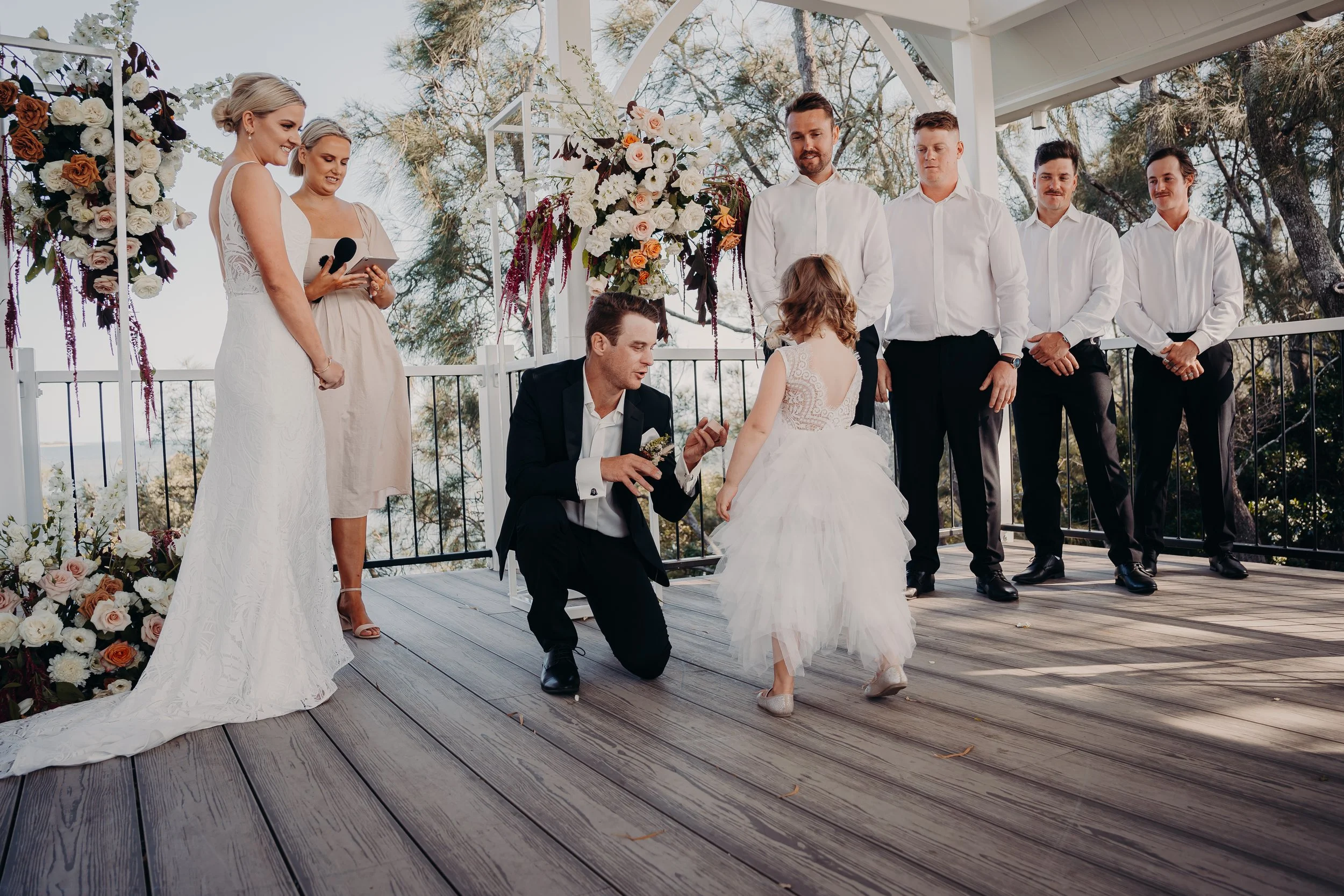 Flower girl giving groom a hug at wedding ceremony.