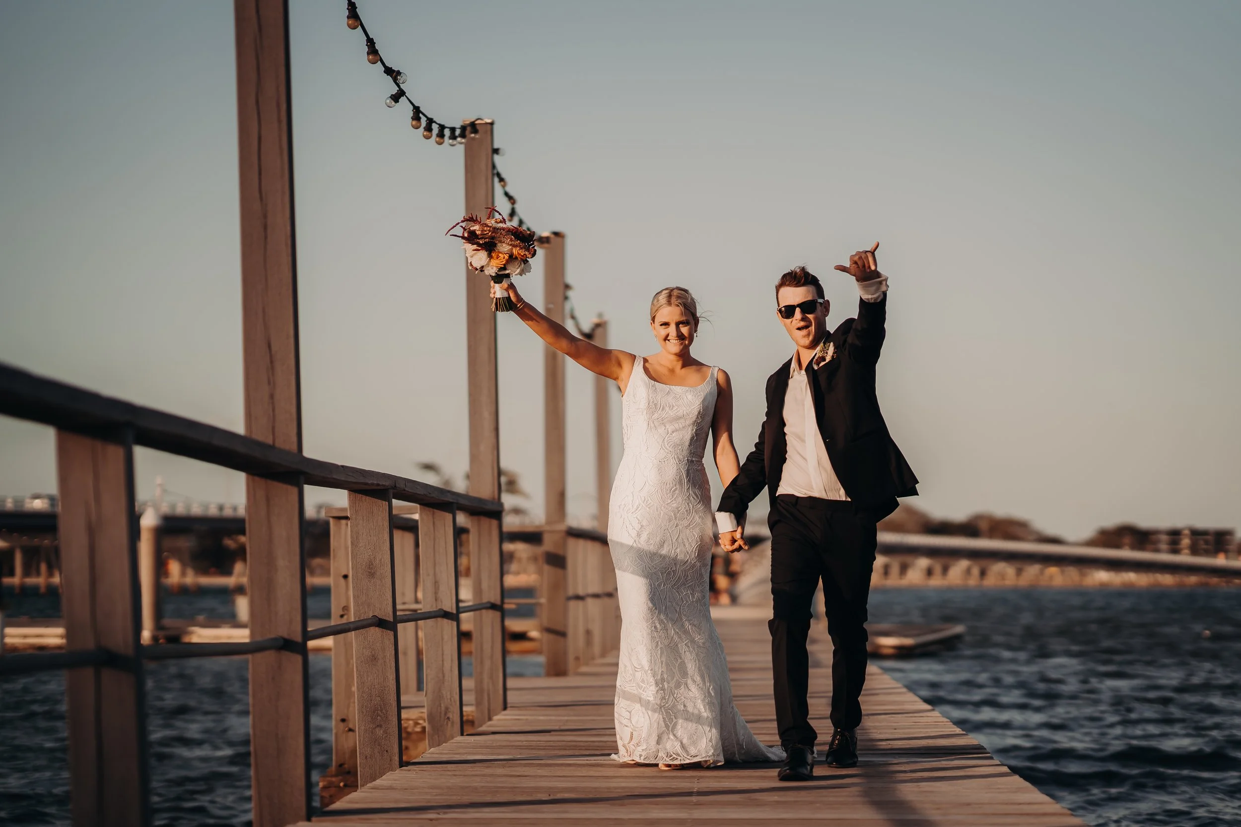 Couple walking along the jetty at Sandstone Point Hotel celebrating