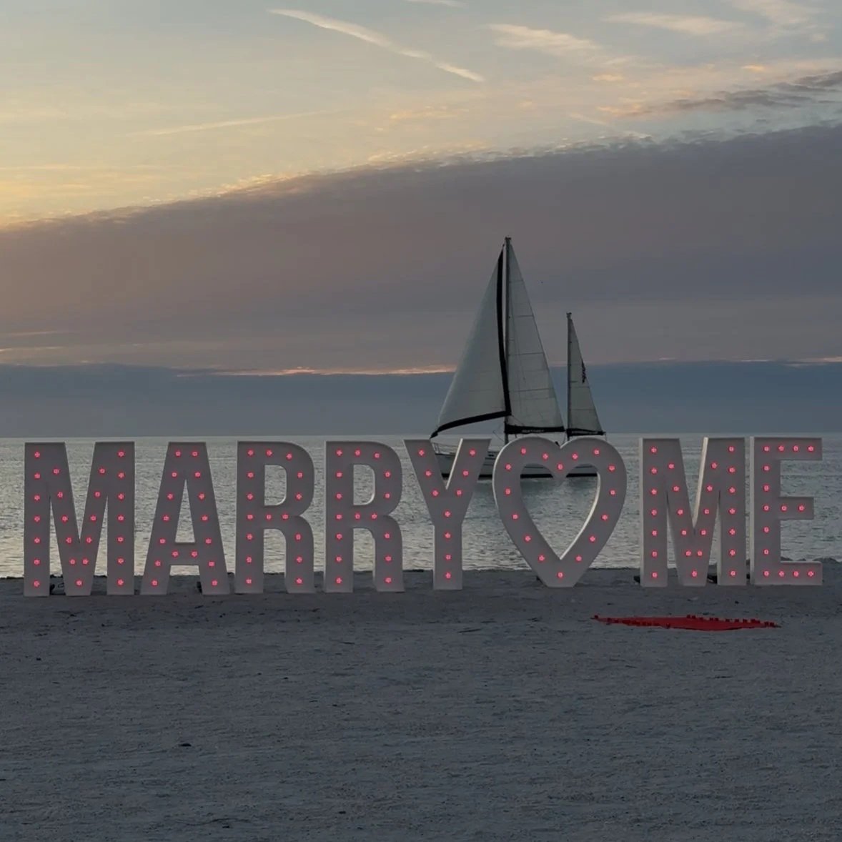 Premium  5ft illuminated "MARRY ME" marquee letter rental on a beach at sunset, creating a romantic proposal backdrop in the Tampa Bay area. Starting at $85 per letter or $75 each for 5+ rentals.