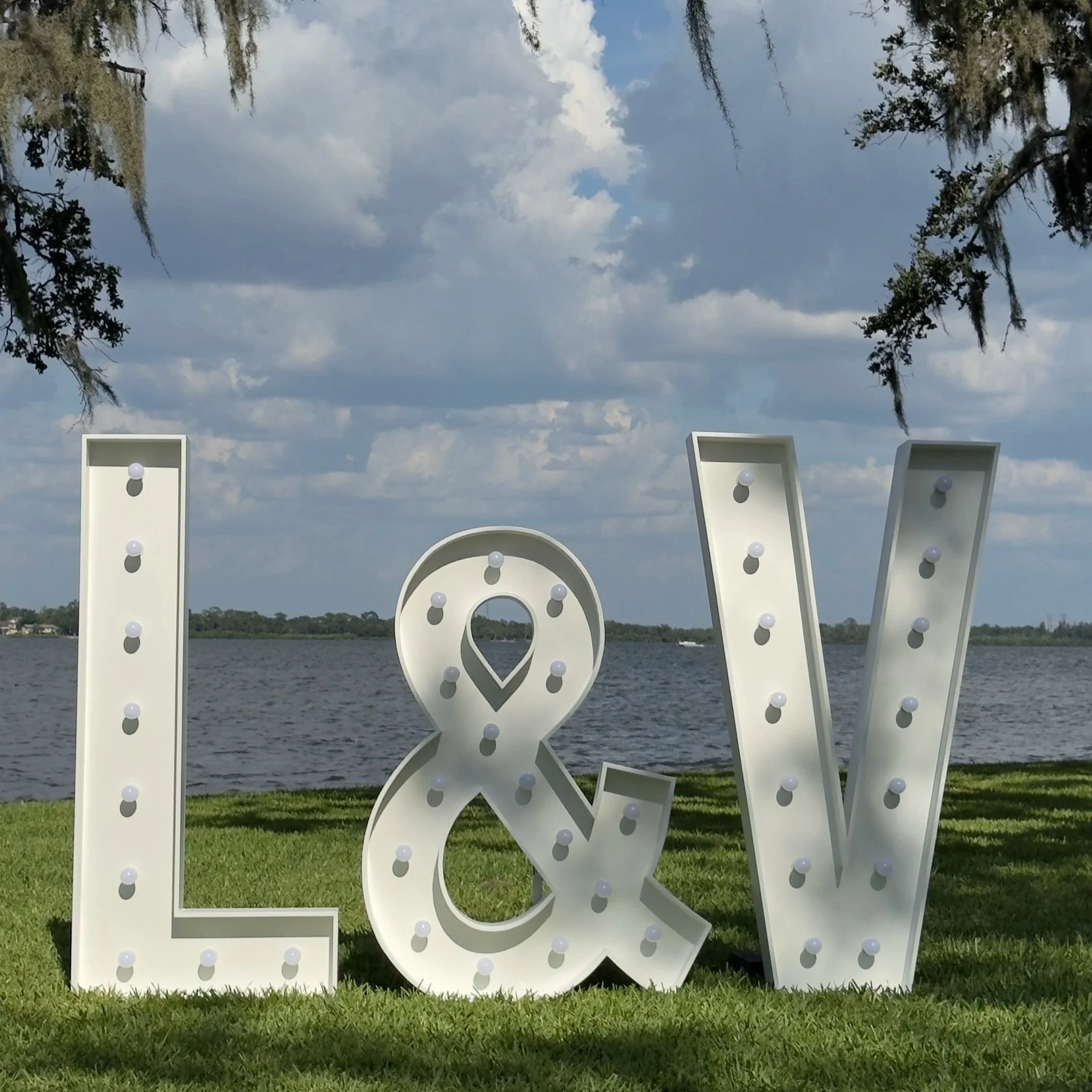 Premium 5ft illuminated L & V marquee letters displayed on a waterfront lawn. Starting at $85 per letter or $75 each for 5+ rentals.