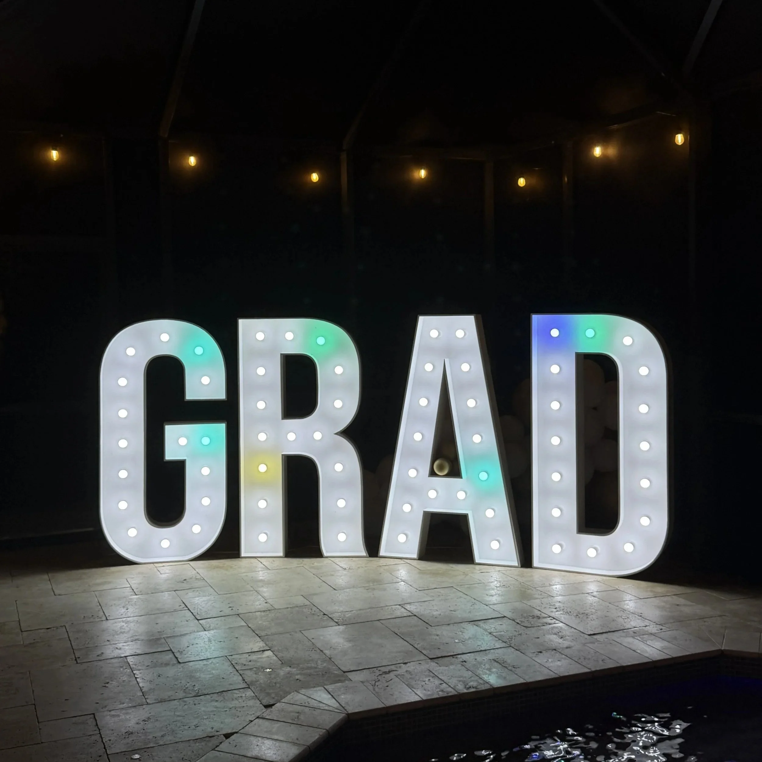 Premium  5ft illuminated GRAD marquee letters displayed poolside for a graduation party.