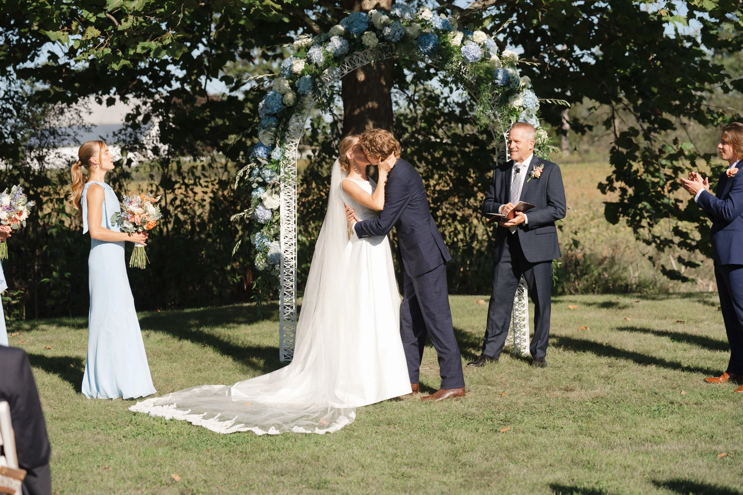 Wedding ceremony bride and groom's first kiss during their outdoor Indiana backyard wedding held at groom's parents house
