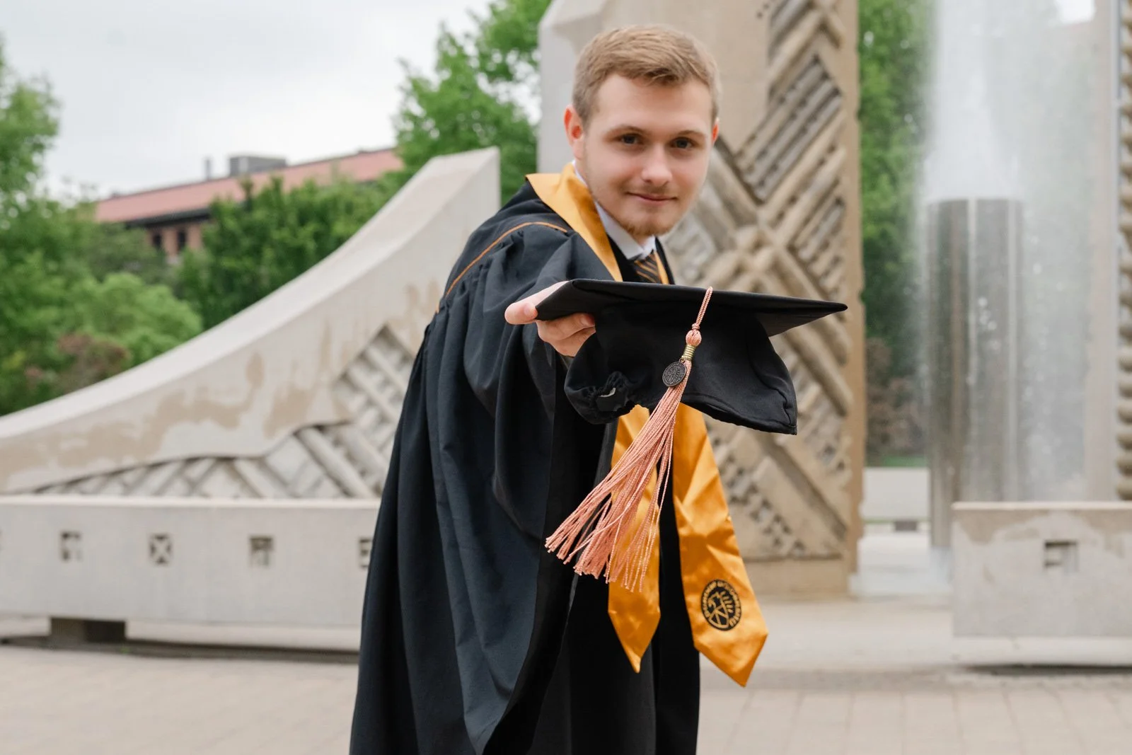 Male Purdue Student tossing cap by the Engineering Fountain during cap and gown picture session with Heather Corbin Photography