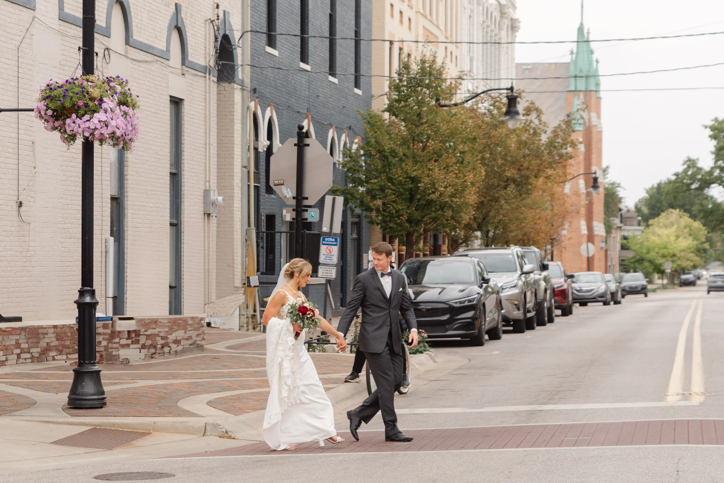Bride and groom crossing main street in downtown Lafayette, Indiana on their wedding day.  Walking from Thomas Duncan Hall to Matchbox co-working space.  Photo by Heather Corbin Photography