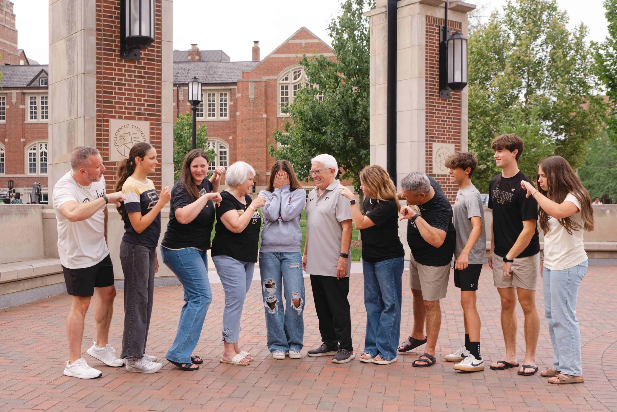 3 generations of family all wearing Purdue shirts except for the high school granddaughter standing in the middle wearing an IU sweatshirt.  the rest of the family is booing.