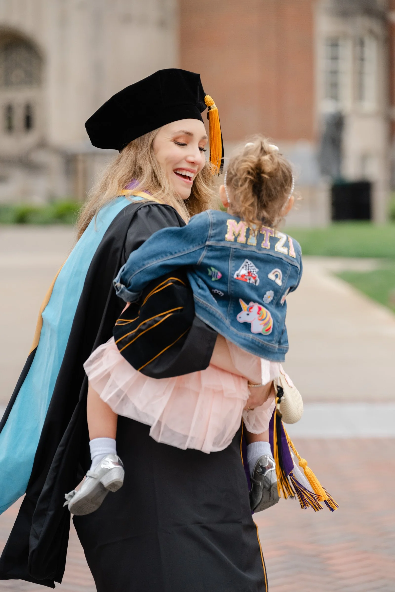 Purdue Global PhD of Education student celebrating graduation in front of the Purdue Union with her 3 year old daughter