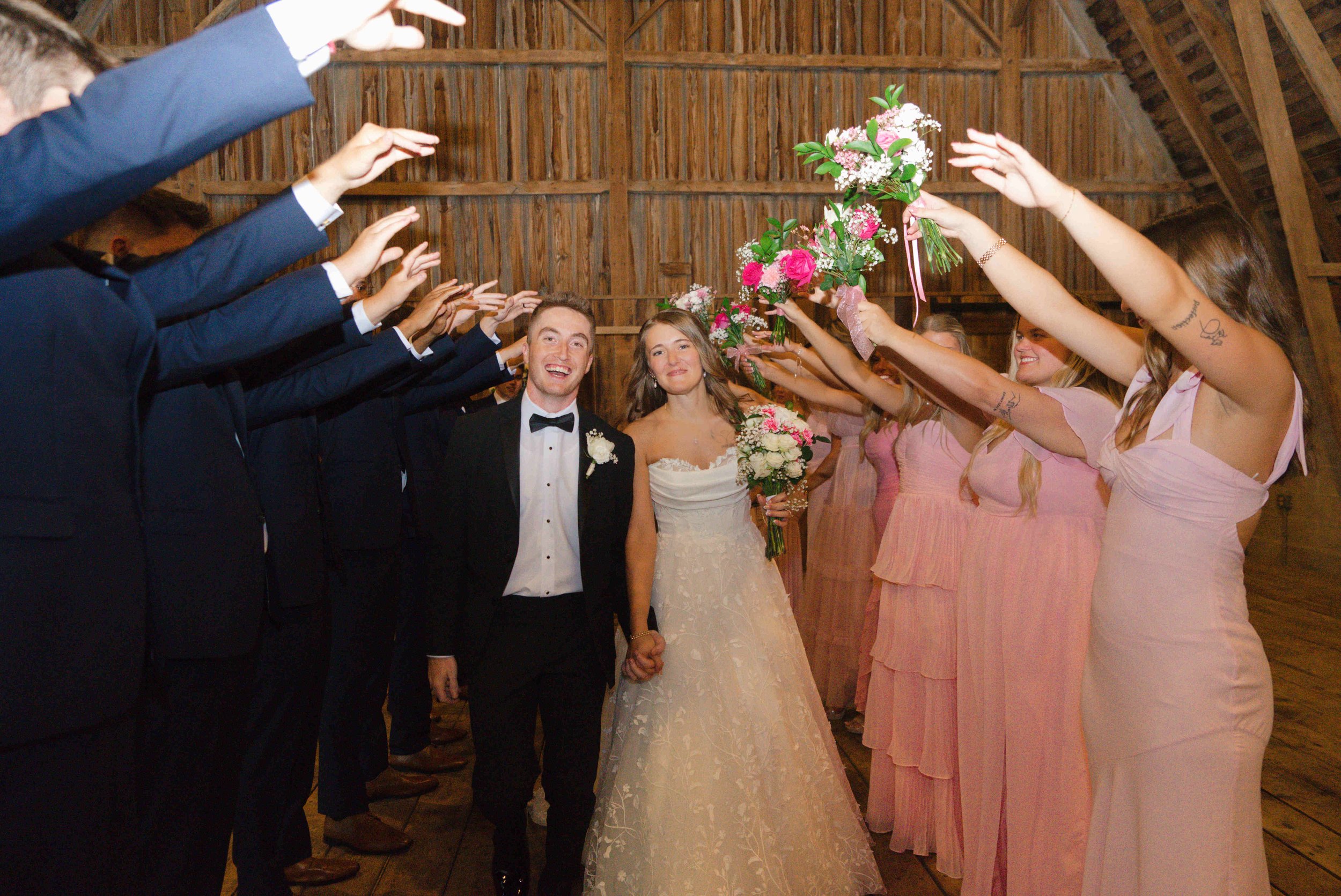 Bride and groom running through a tunnel made up of their bridal party