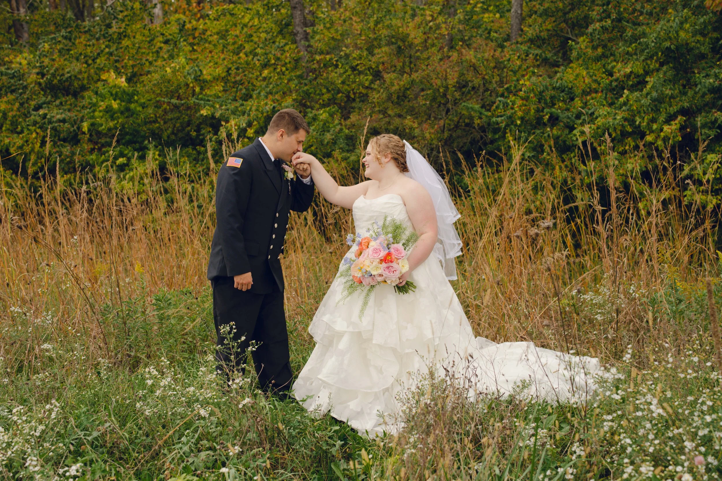 Groom in firefighter dress uniform kissing the hand of his bride.