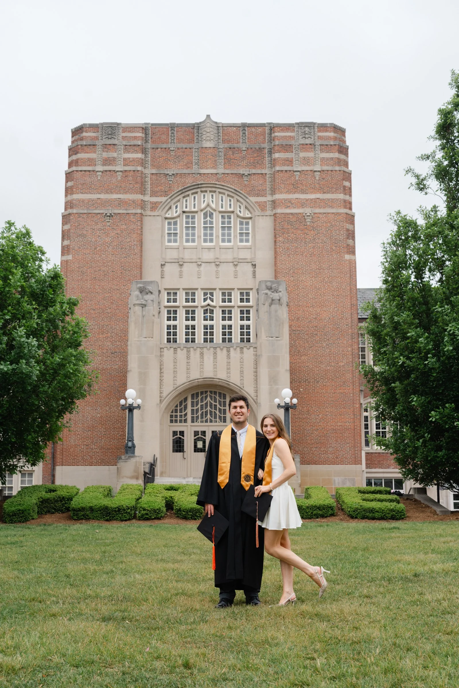 Graduating couple posed in front of the Purdue Union during their Purdue Graduation Photo session.  Picture by Heather Corbin Photography