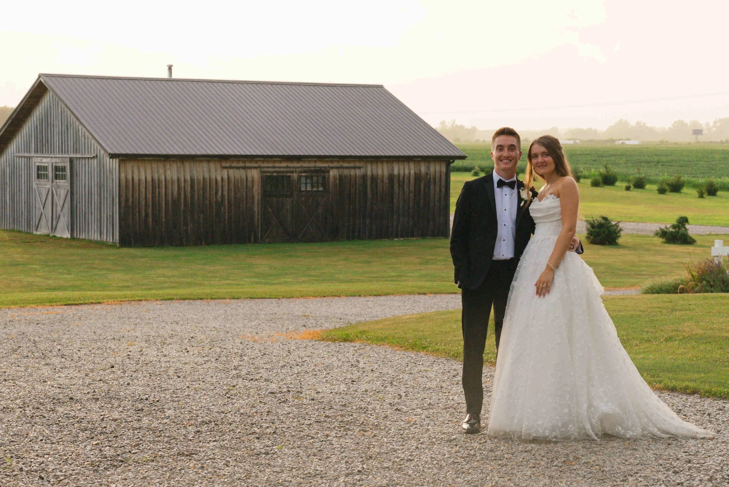 Bride and groom looking at the camera with setting sun in the background after rain finally let up