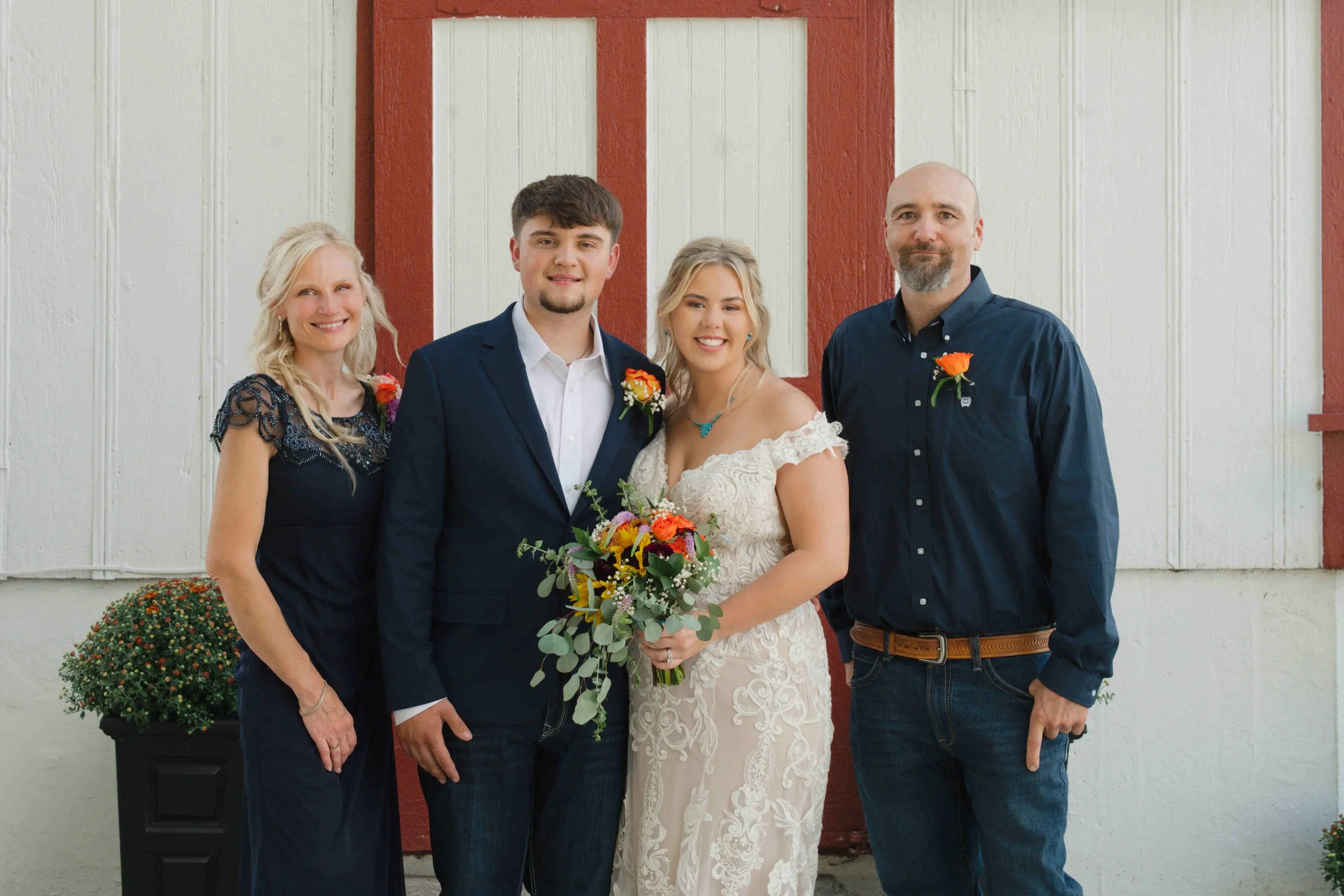 Bride and groom posing with groom's parents for a family photo in front of Governor's Pavilion.  Photo by Heather Corbin Photography