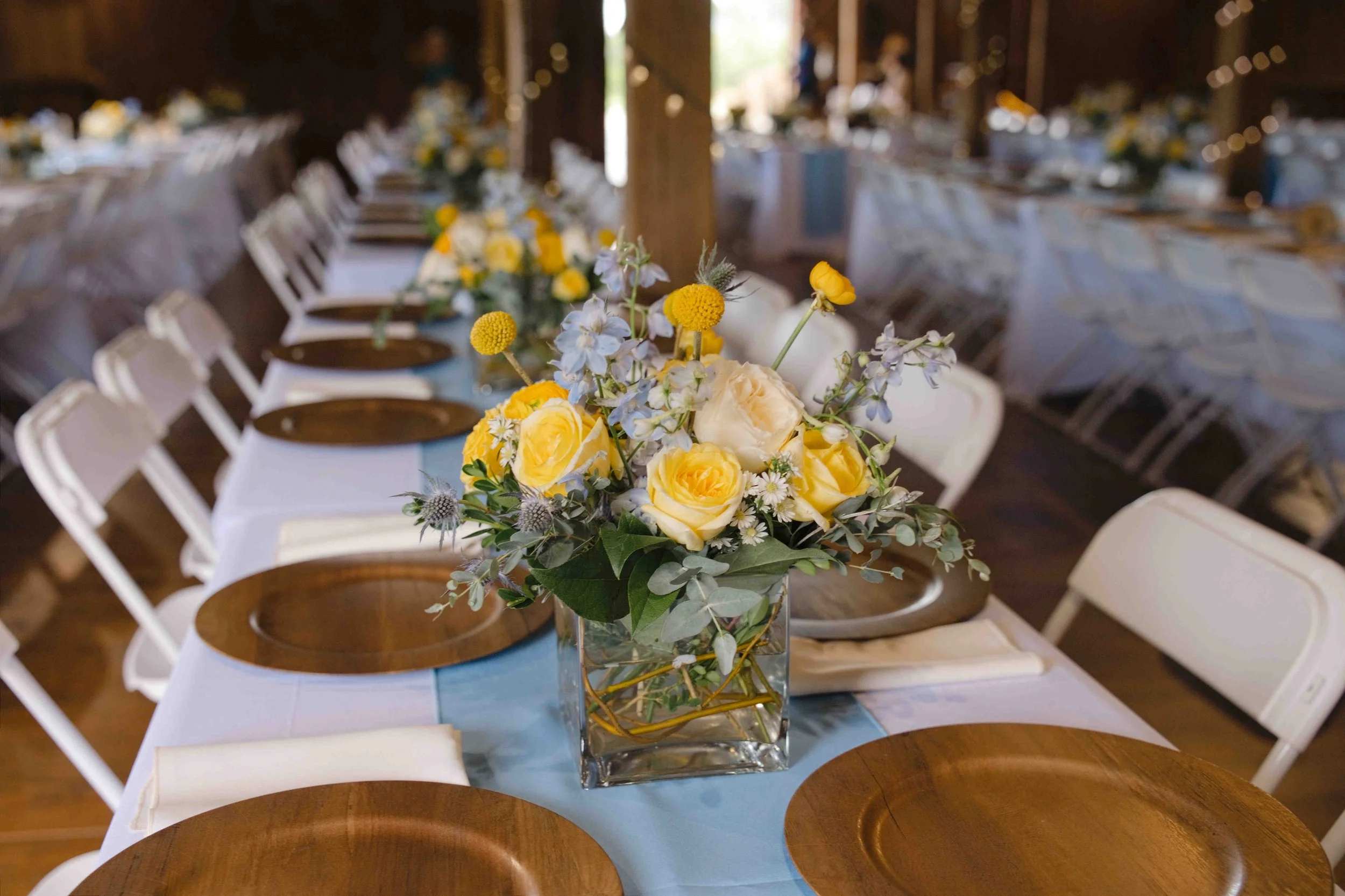 Yellow and blue flowers on reception tables at The Rustic Barn at Hopewell.  photo by Heather Corbin Photography