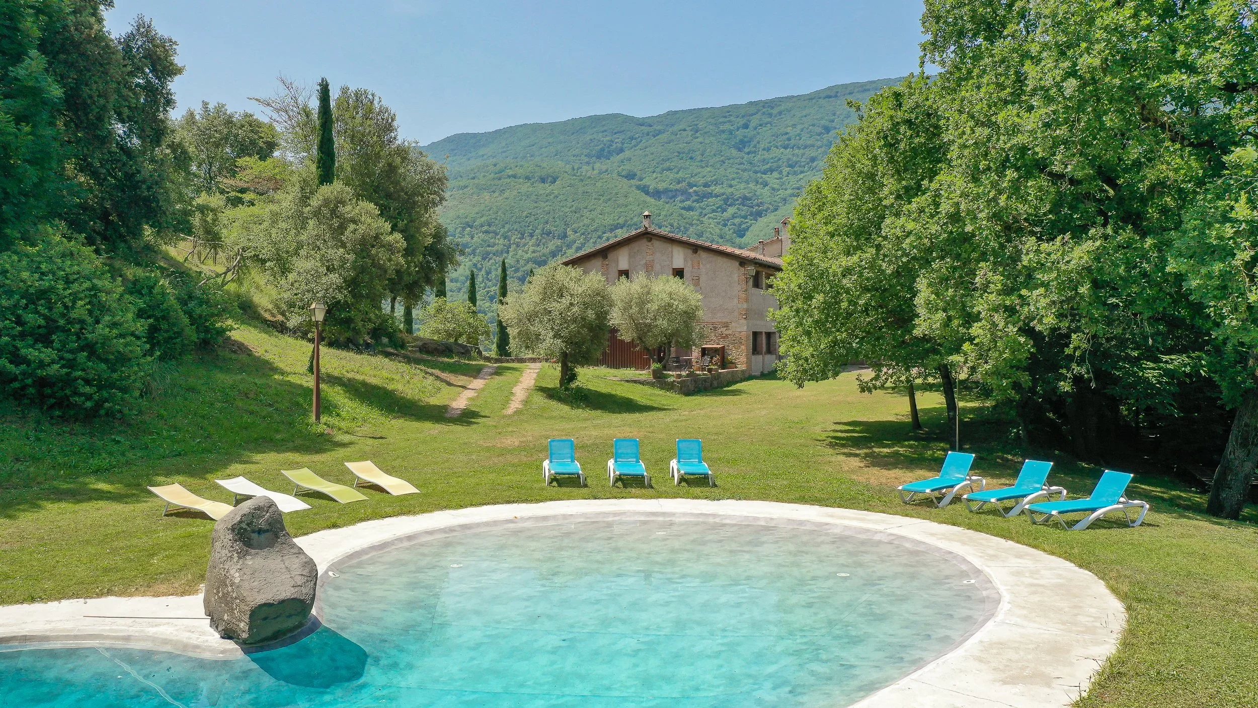 Privater Swimmingpool und Garten in einer ländlichen Ferienwohnung in Girona mit traditionellem Steinhaus, Bergkulisse, Sonnenliegen und üppiger Naturumgebung — Ferienunterkunft in der katalanischen Landschaft.