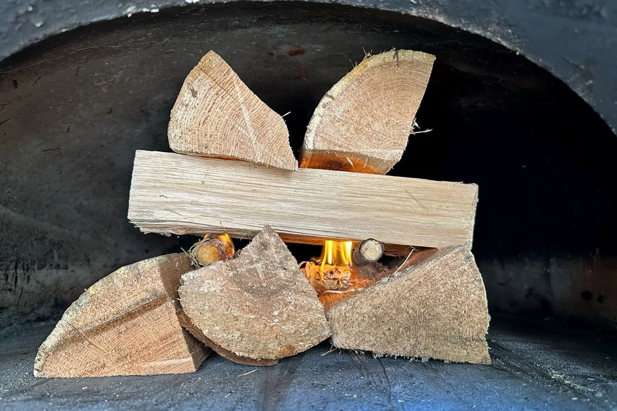 Brick oven starter fire and wood stack.