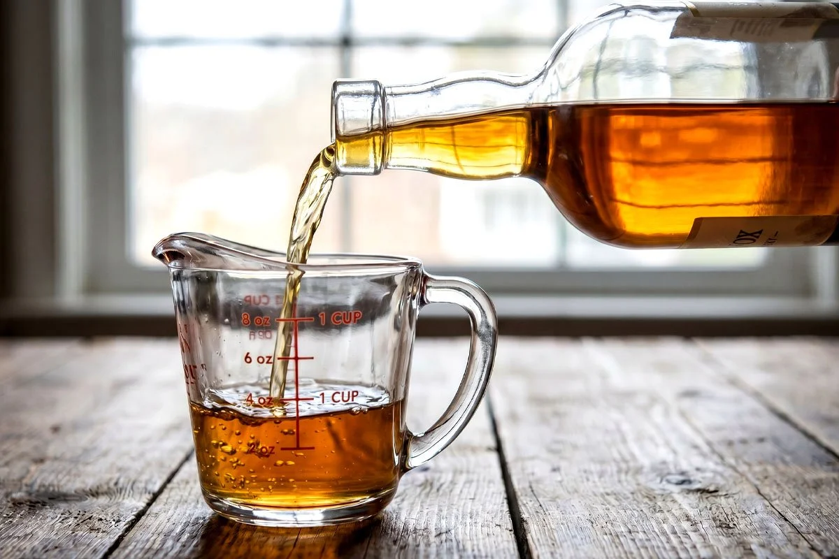 Whisky being poured into a measuring cup.