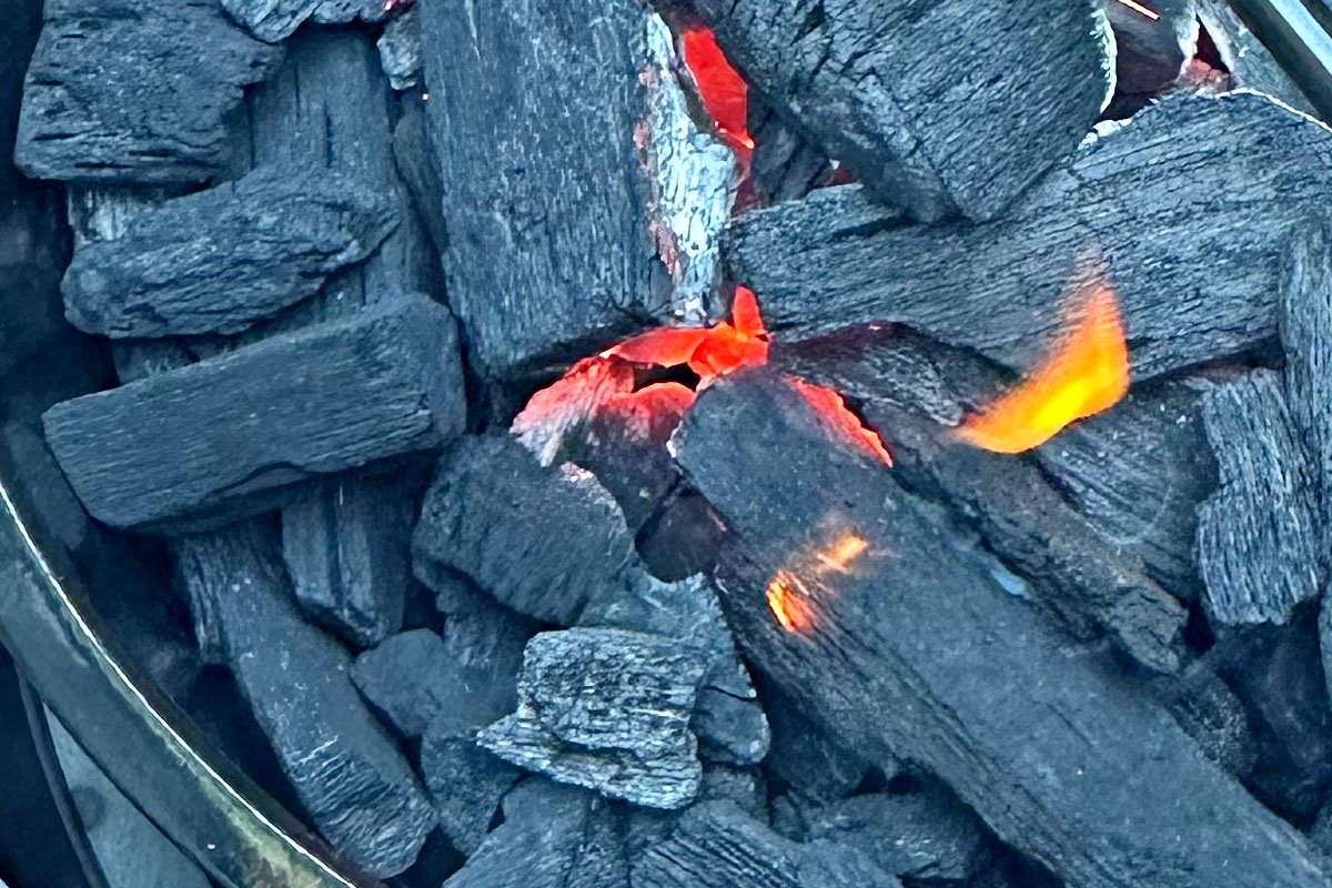 Lump charcoal starting to burn into coals.