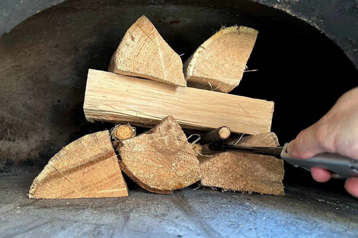 Three layers of wood in a brick oven, ready to light a fire.