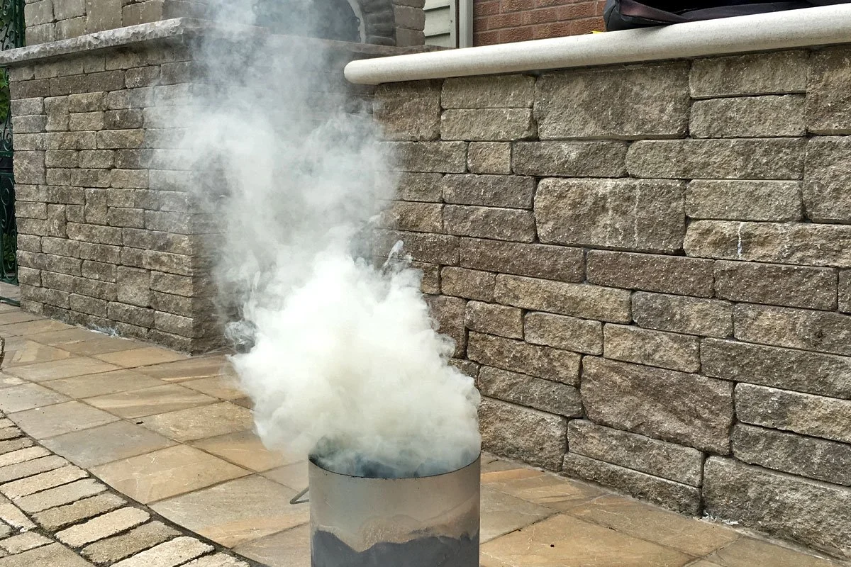 Smoke from hardwood lump charcoal in a charcoal chimney.