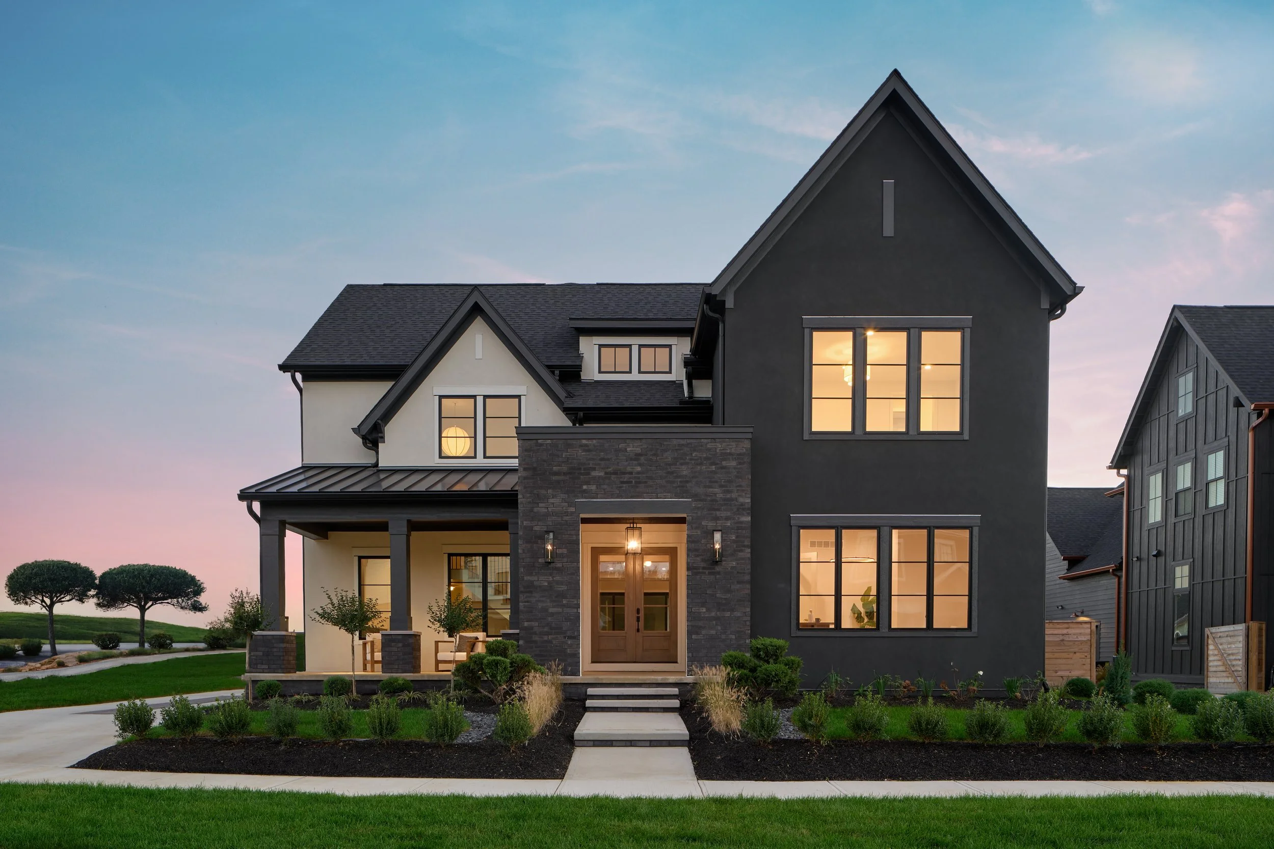 Black and white stucco modern house. Japandi style with gas lanterns on brick parapet entry. Shoji White and Iron Ore colors with Pella Lifestyle Casement Windows.