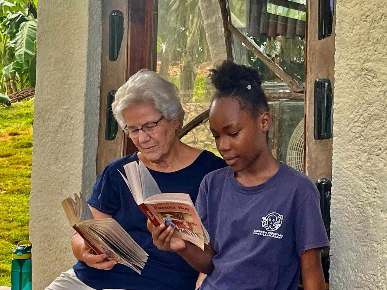 Dominican student reading with volunteer missionary teacher