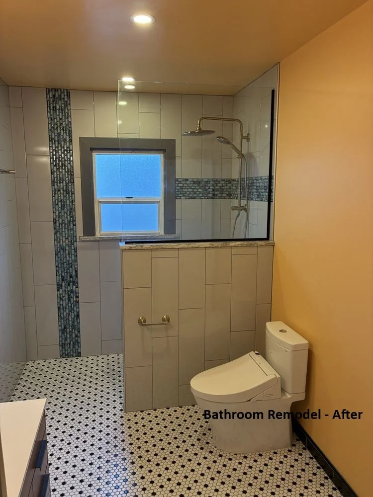 "After" photo of that same older bathroom now renovated with a glass shower enclosure, tiled walls, a window, and a modern toilet. The floor has small black and white mosaic tiles, and the walls are painted light yellow.