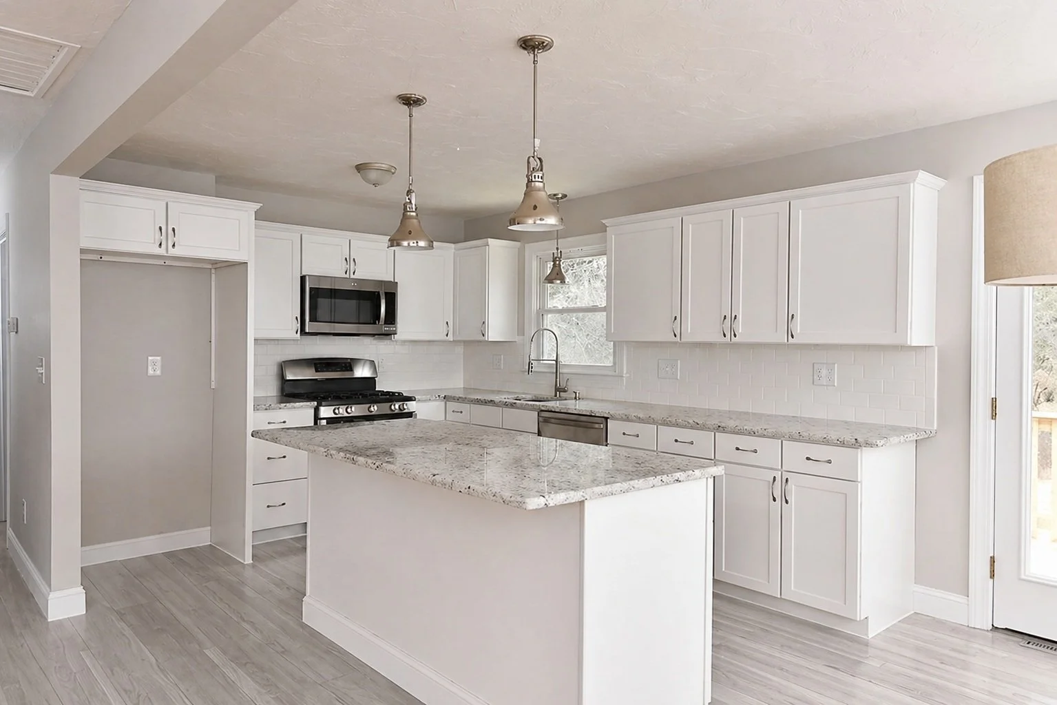 Modern kitchen with white cabinets, granite countertops, a hanging light fixture, stainless steel appliances, and a window above the sink.