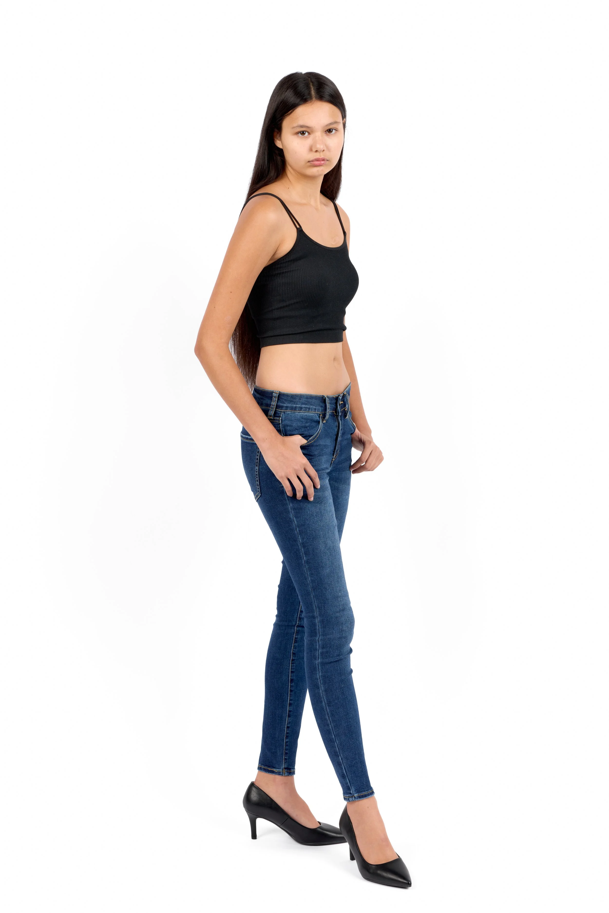 Chicago Modelling Digital of a young woman with long dark hair standing in a pose against a plain white background. She is wearing a black crop top, blue jeans, and black high heels.
