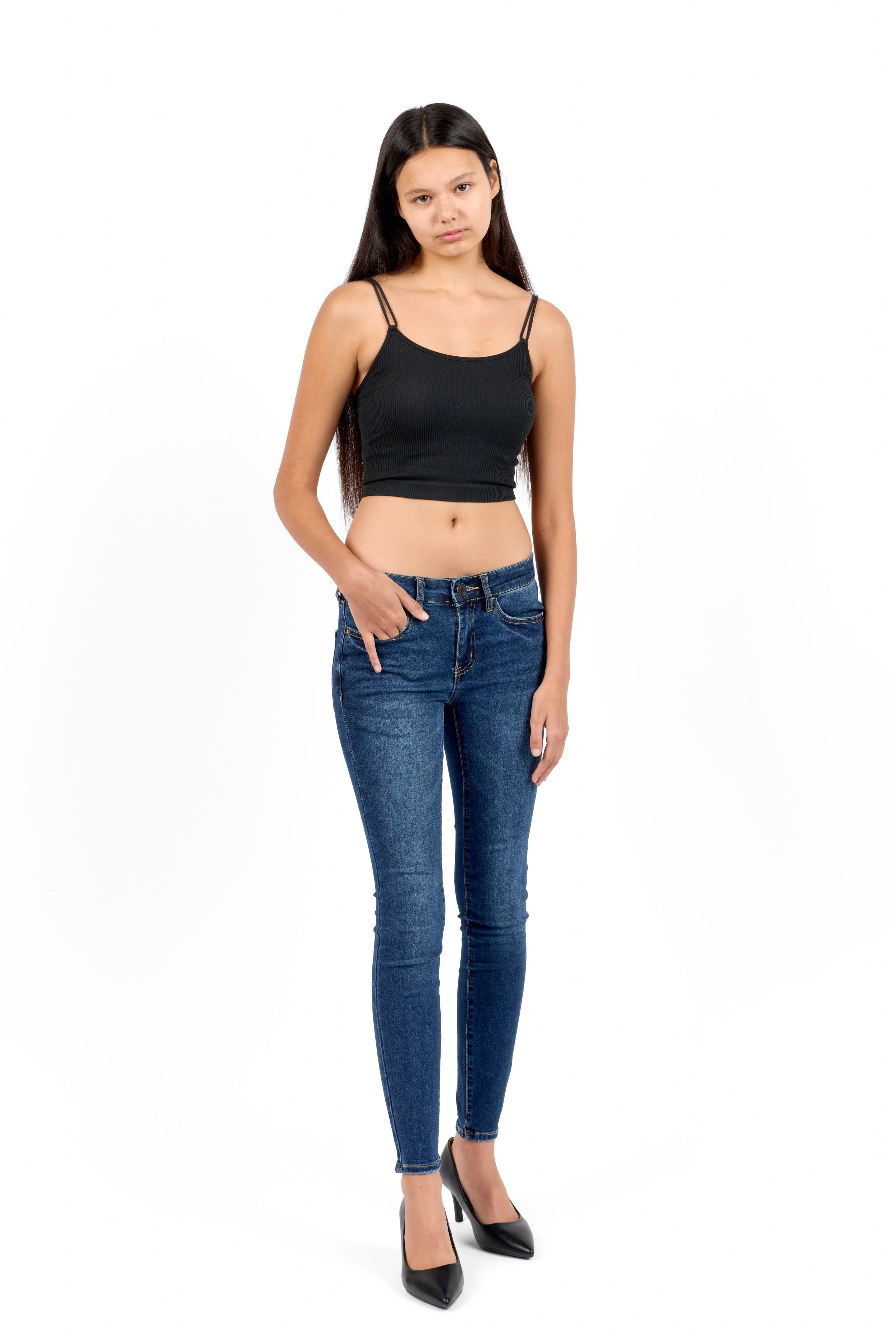 Chicago Modelling Digital of a young woman with long dark hair wearing a black spaghetti strap crop top, blue jeans, and black high heels, standing against a plain white background.