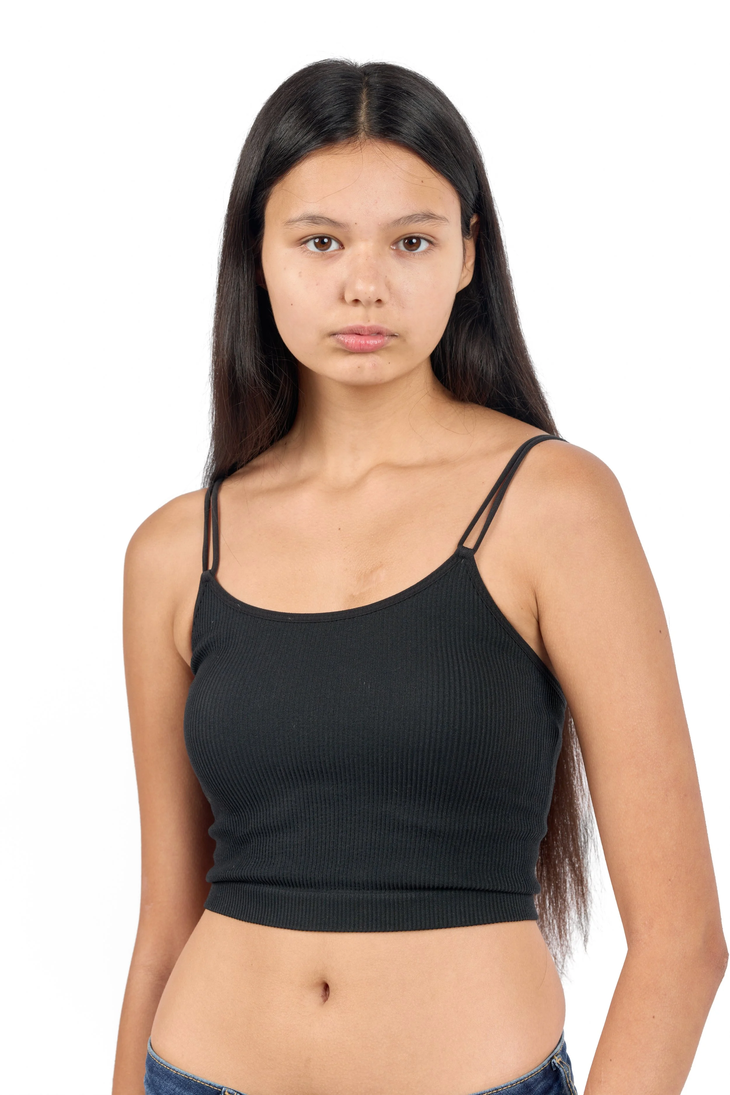 Chicago Modelling Digital of a young woman with long dark hair, wearing a black sleeveless top and blue jeans, standing against a plain white background.