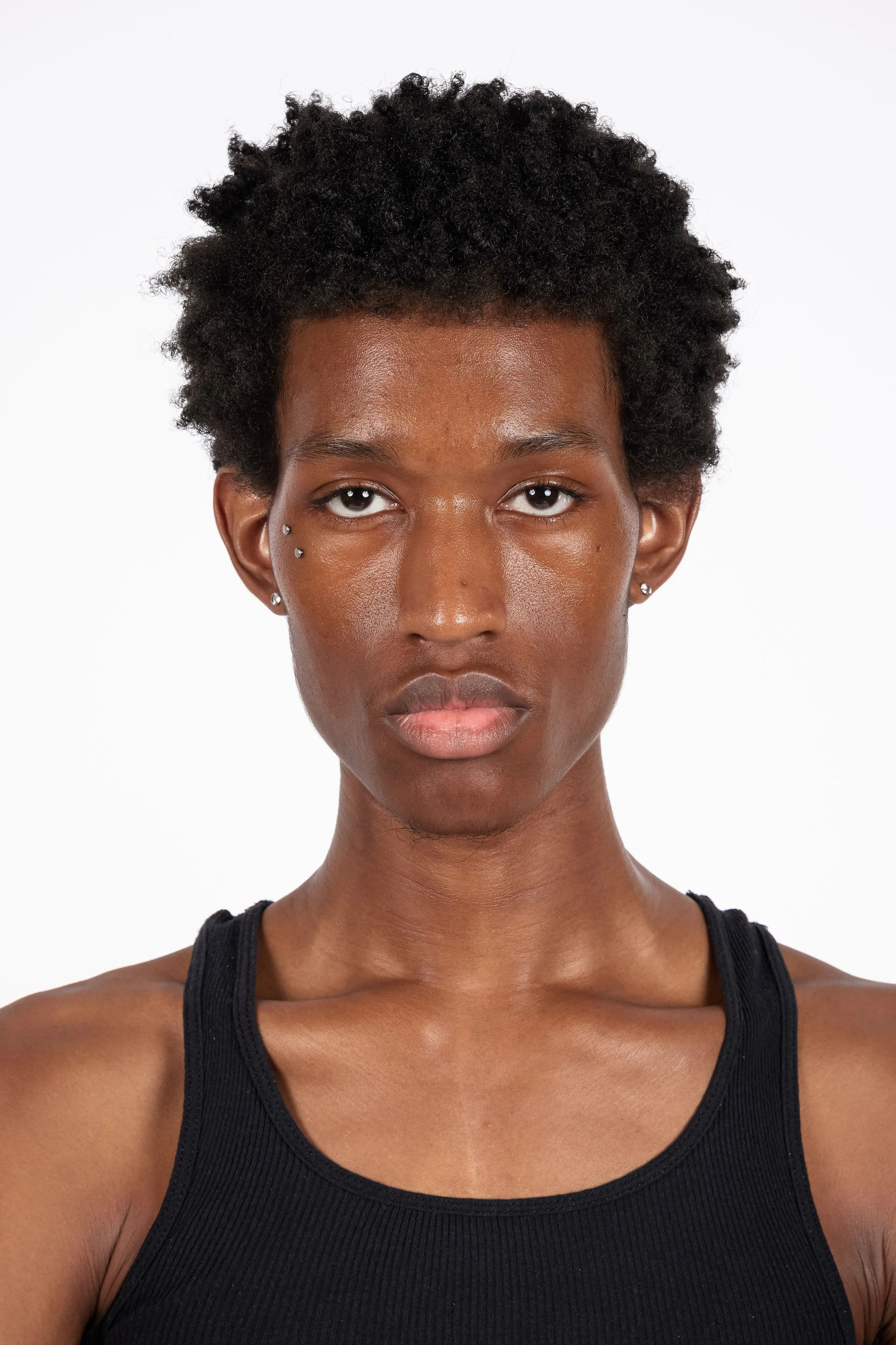 Chicago Modelling Digital of a young man with natural curly hair, wearing a black tank top, against a white background.