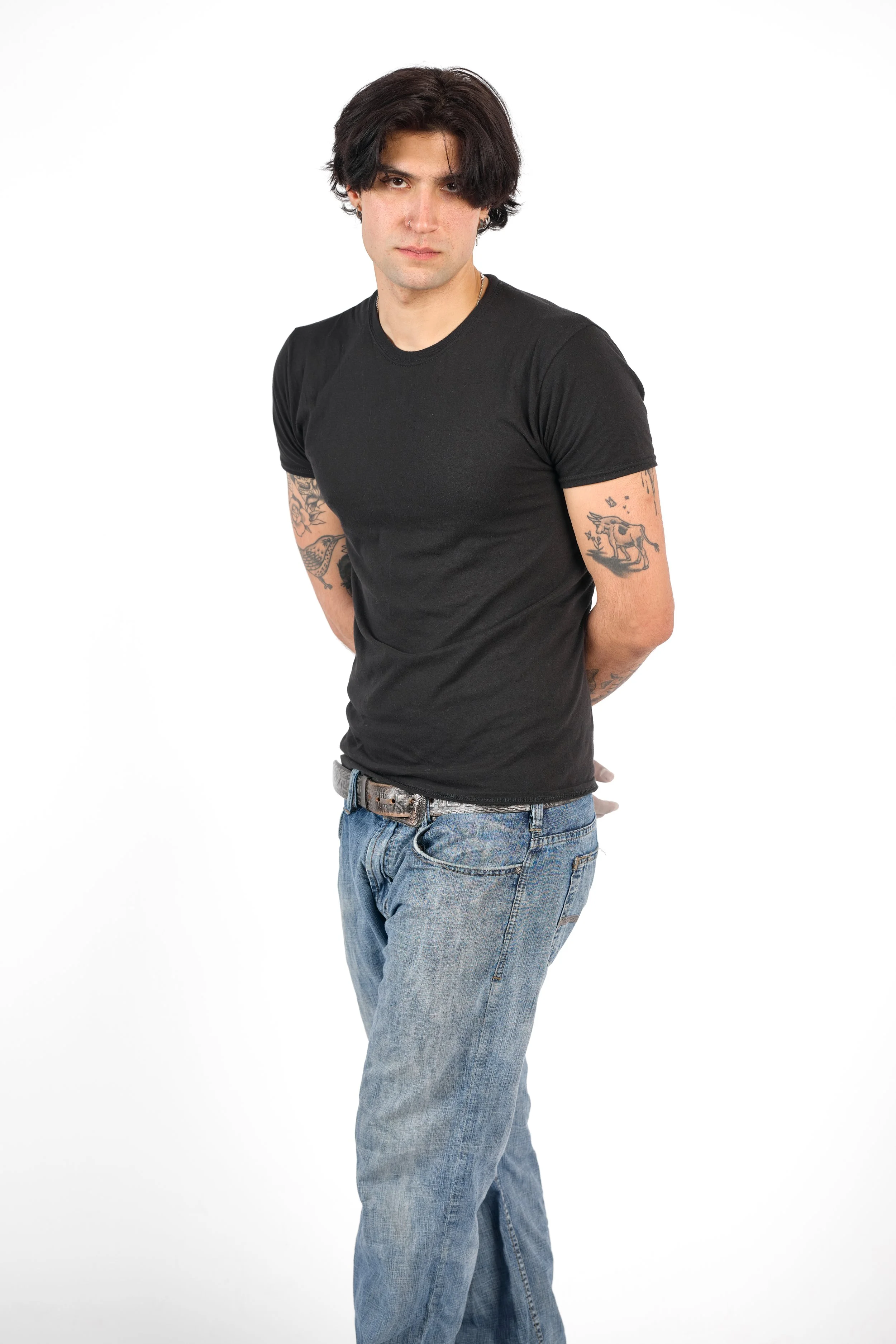Chicago Modelling Digital of a young man with dark hair, tattoos on arms, wearing a black t-shirt and blue jeans against a white background.