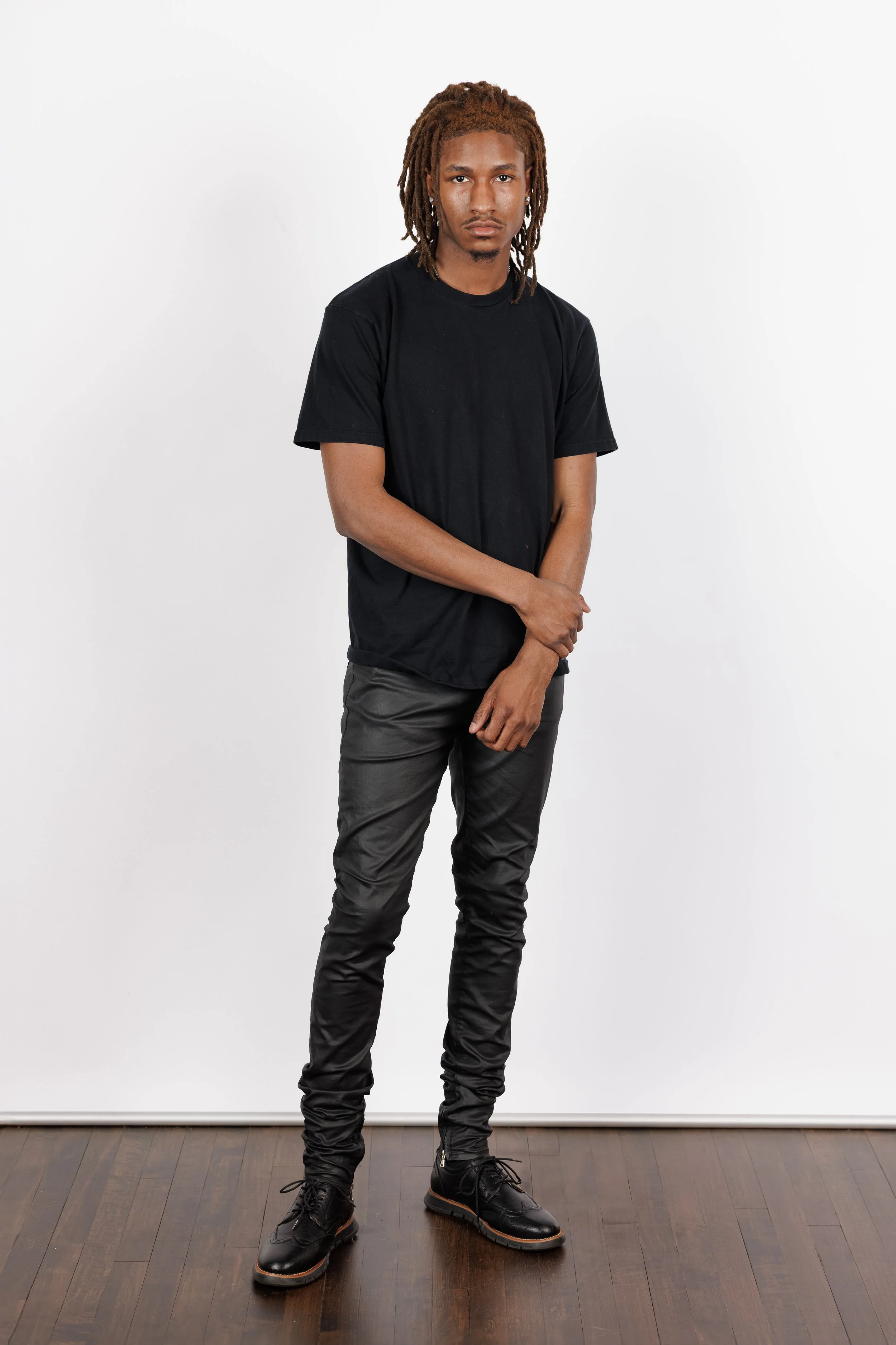 Chicago Modelling Digital of a young man with dreadlocks wearing a black t-shirt, black pants, and black shoes standing against a plain white background.