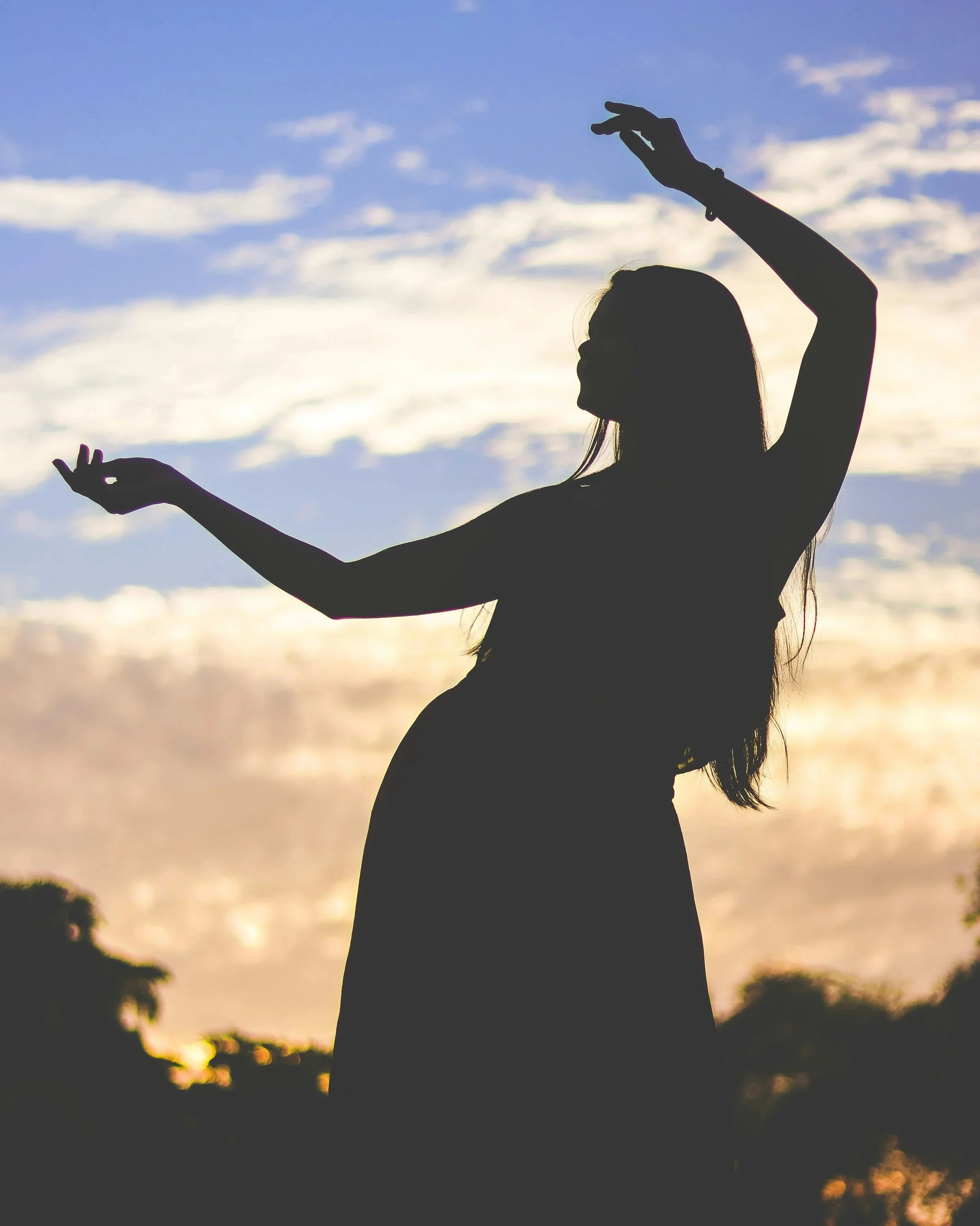 Silhouette of a woman moving freely with a sunrise in the background