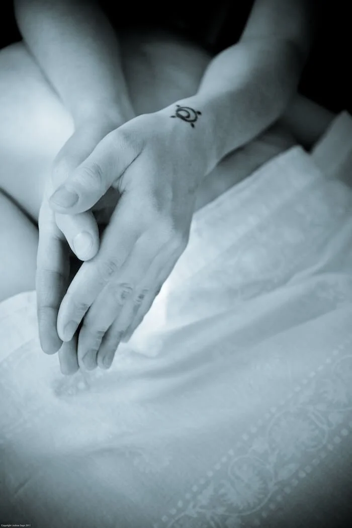 muse's hands held together in a loose prayer position as she leans her forearms into the body of her receiver, drapes in white patterned cloth