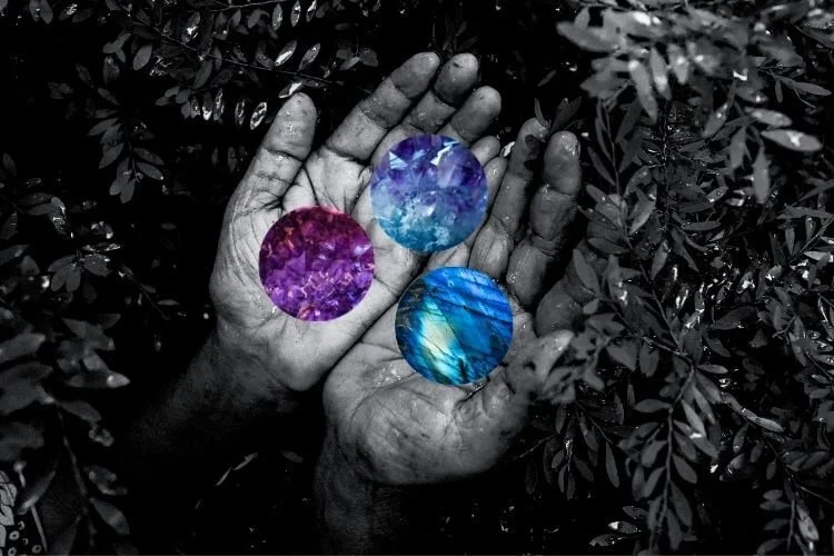 two hands held together, palms open, holding three crystal spheres