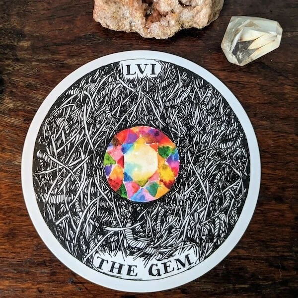 the gem card from the archetypes deck by kim krans, on a wooden table beneath a rough pink crystal