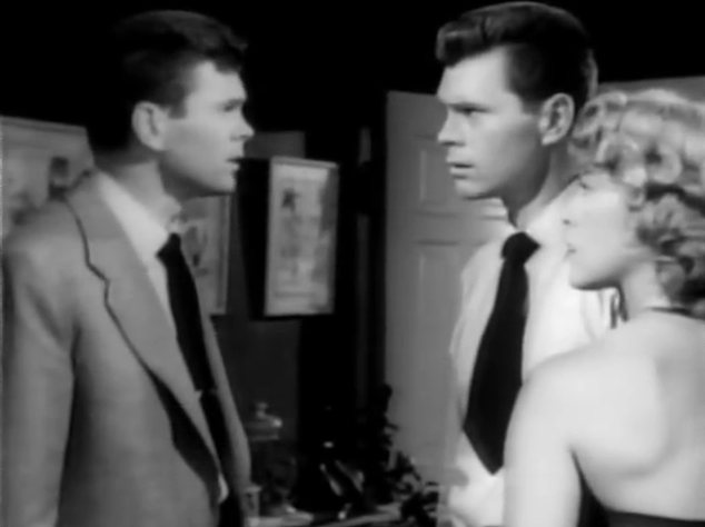 Two basically identical guys looking at each other in a house, with a woman on the right of the frame with the imposter, who has this guys face!